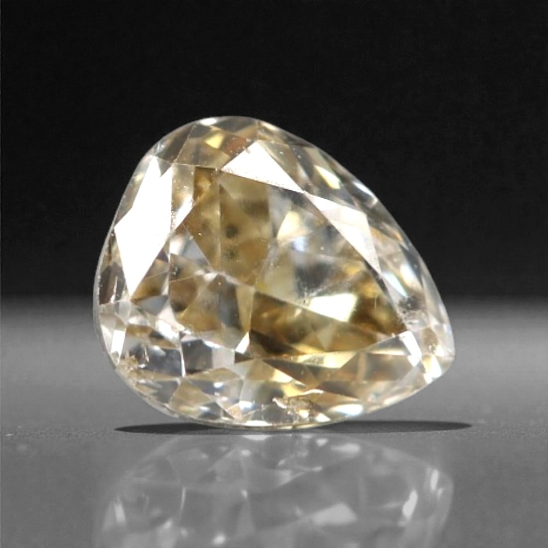 0.17 Carats Fancy Light Brownish Yellow Diamond - Natural South African Origin, 1DA: This exquisite fancy light brownish yellow diamond captivates with a warm, honeyed hue that radiates softly across its faceted surface, creating a gentle, inviting glow. The pear-shaped cut enhances t