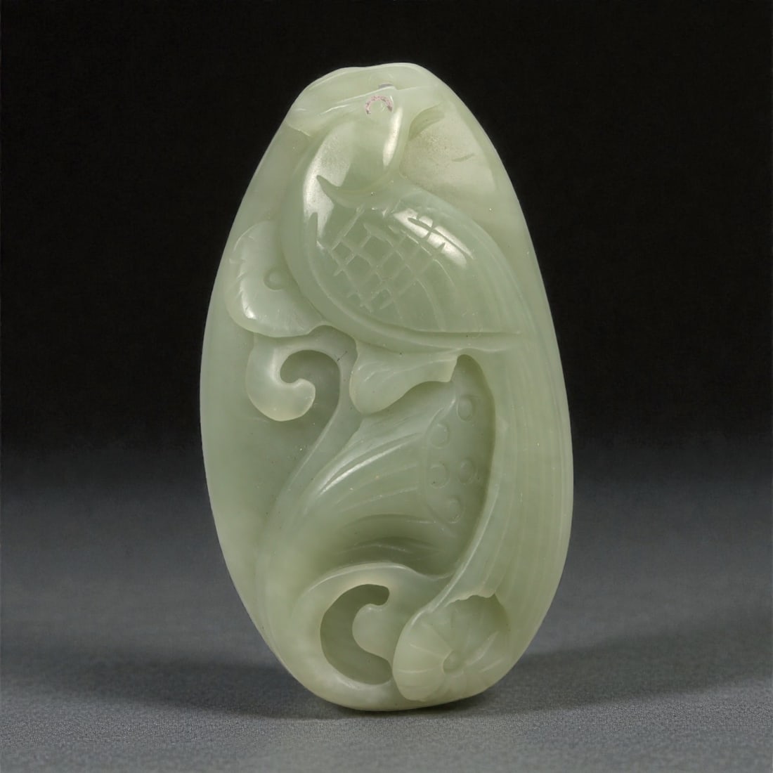 A Chinese Nephrite Jade Relief Plaque, 20th Century, 48YA: Carved from pale celadon nephrite jade with a soft, even translucency and minor natural inclusions, the plaque is worked in low relief depicting a stylized bird amid scrolling vegetal and cloud-like f
