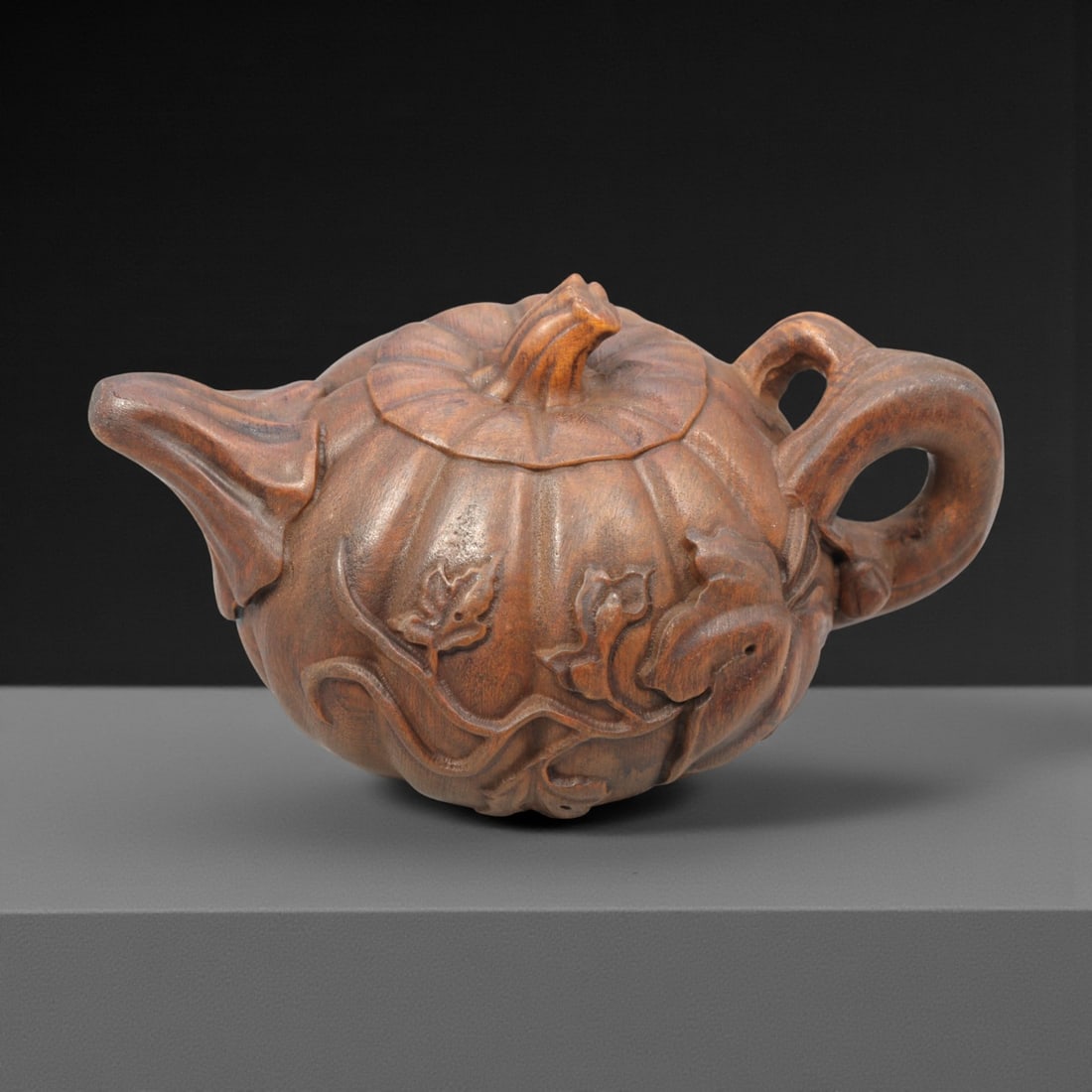 A Chinese Wood Teapot Sculpture, 20th Century, 58FH: Carved from a single block of hardwood with a warm brown tone and visible natural grain, the object is modeled in the form of a teapot with an integrated lid, spout, and handle. The body is rendered a