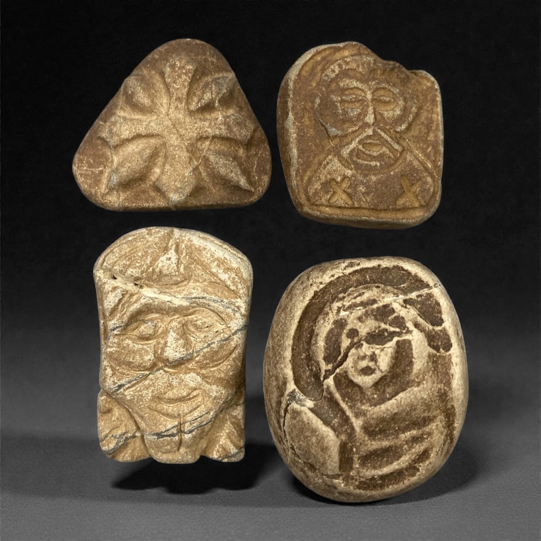 A Group of Four Christian Period Stone Carving Reliefs, 4th-7th Century, 4FN: Carved from stone with natural patination, mineral inclusions, and surface wear, the four reliefs depict distinct iconographic elements. The top-left relief is triangular, featuring a stylized floral