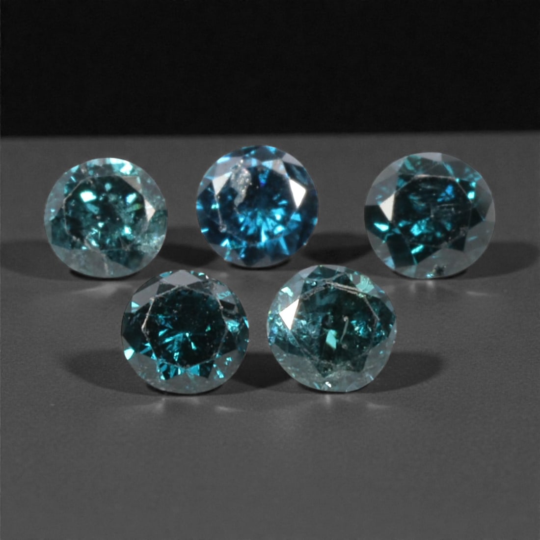 5 Pieces Irradiated Blue Diamond Parcel - Round Brilliant Cut, 2.4mm, 245A: This striking parcel of five loose irradiated blue diamond gems captivates with a vivid, cool blue hue that evokes the intensity of a deep ocean and the clarity of a winter sky. Each stone is cut in a