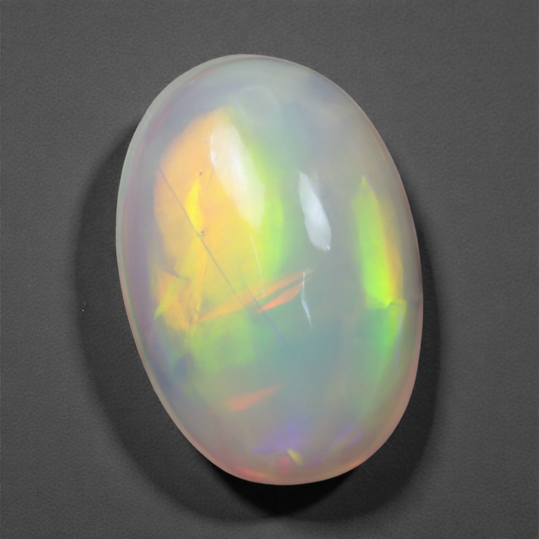 3.70 Carats Neon Flash Welo Opal - Natural Ethiopian Gemstone 14.2x9.8x5.8mm, 46XH: A mesmerizing display of luminous fire radiates through this translucent Welo opal, featuring bold flashes of green, gold, and violet under light. The gem's internal play-of-color shifts dramatically