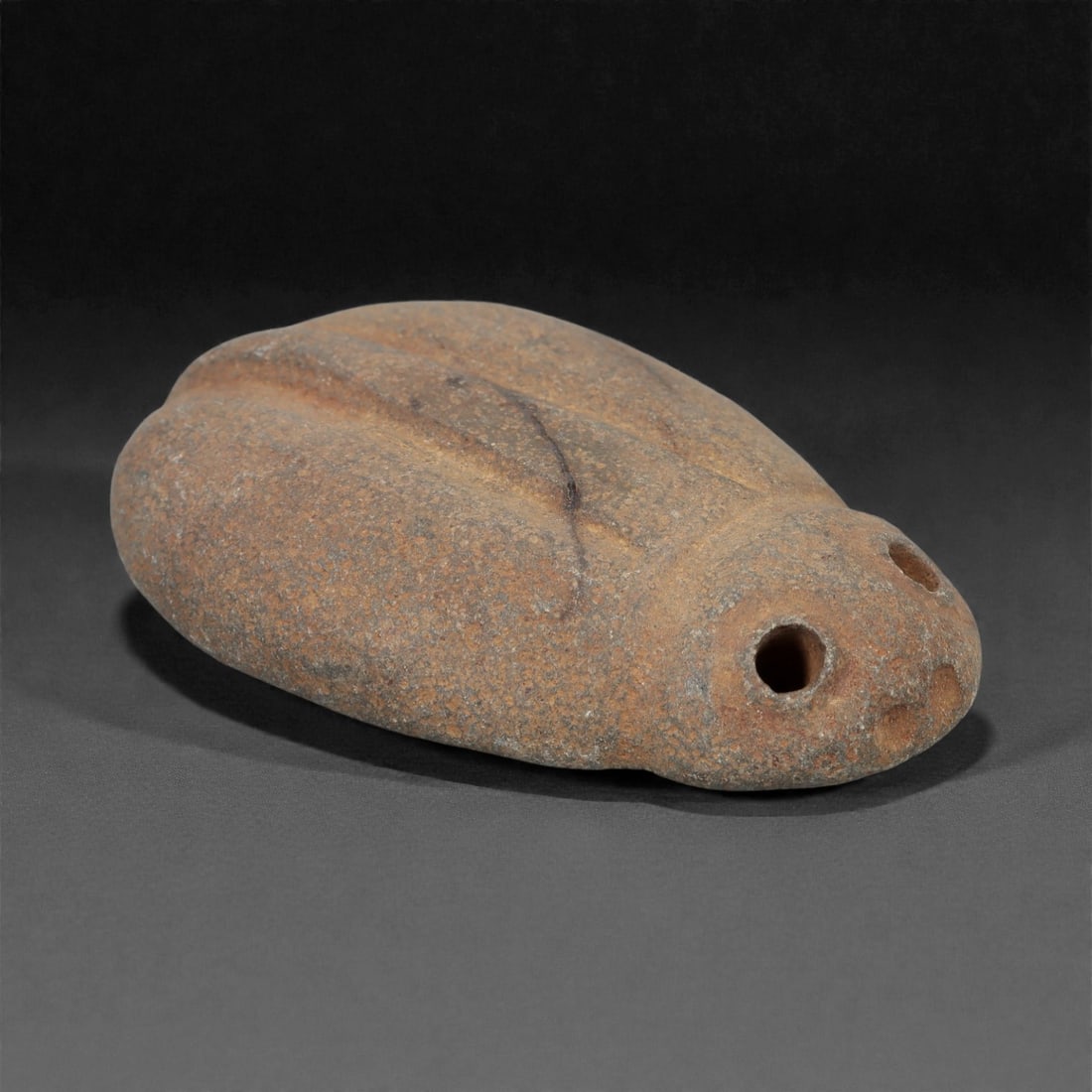 A Near Eastern Stone Scarab, 3rd-2nd Millennium BCE, 5FM: Carved from speckled brownish-grey stone with natural surface patination and minor linear fissures, the object is formed as an oval scarab with multiple perforations for suspension. The dorsal surface