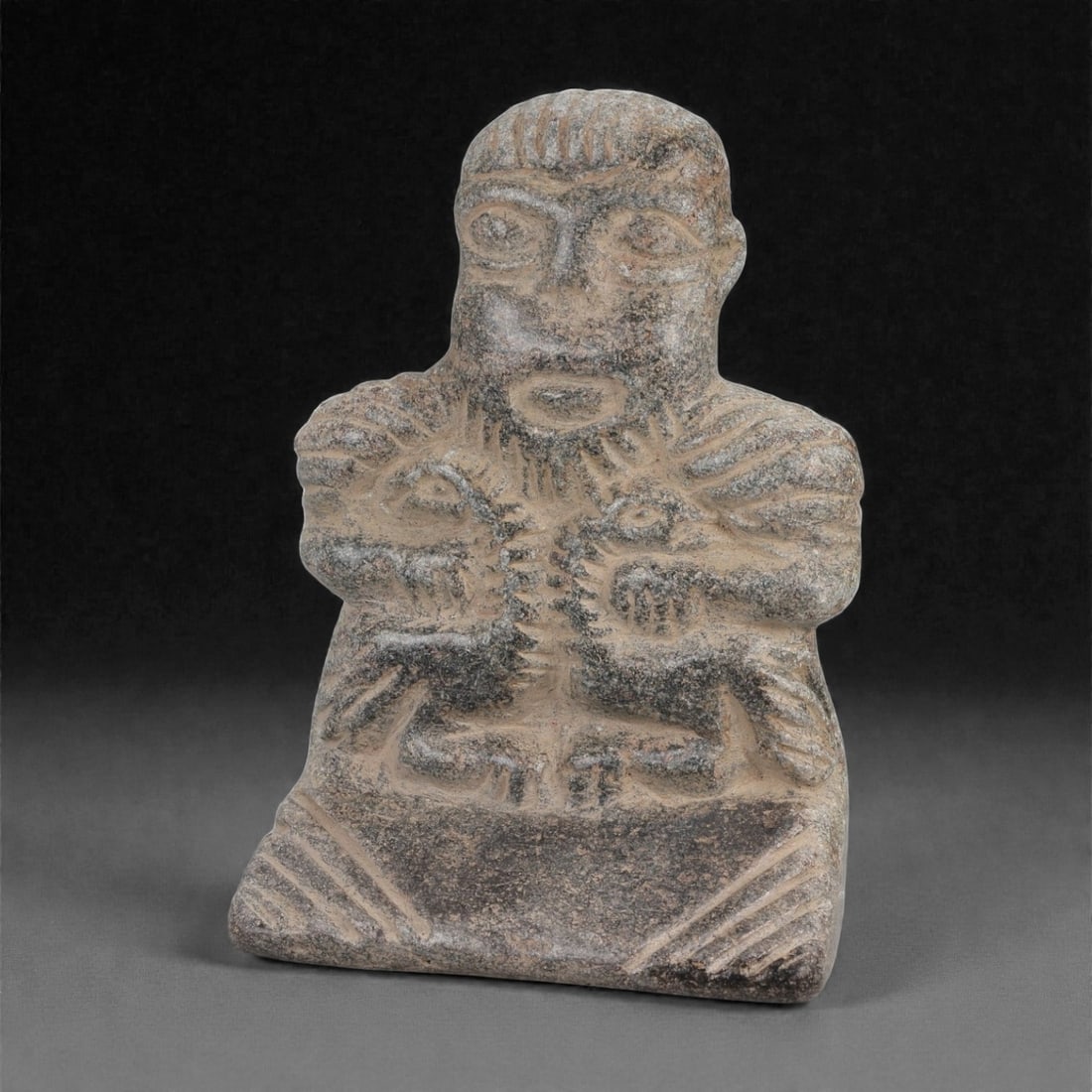 A Syro-Mesopotamian Schist Standing Figure, Early 2nd Millennium BCE, 60LK: Carved from grey schist with a flat back and a squared lower base, the figure is shown frontally with a large head, circular recessed eyes, a short rounded mouth, and incised striations across the for