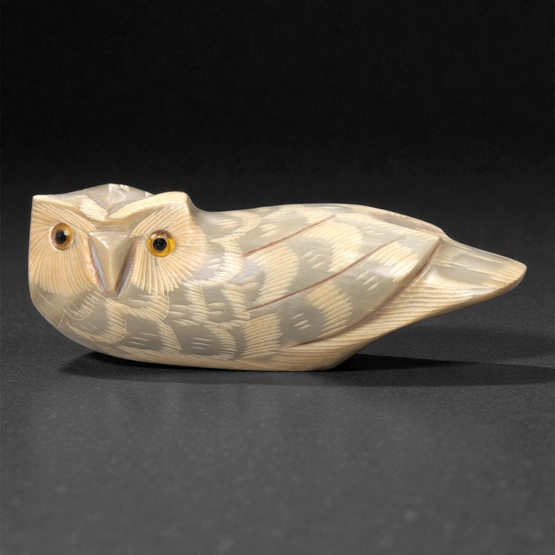 An East Asian Ox Horn Owl Effigy, 20th Century, 14FJ: Carved from a single section of pale ox horn with subtle natural striations and a smoothly polished surface, the effigy is modeled as a recumbent owl rendered in the round. The head is broad and flatt