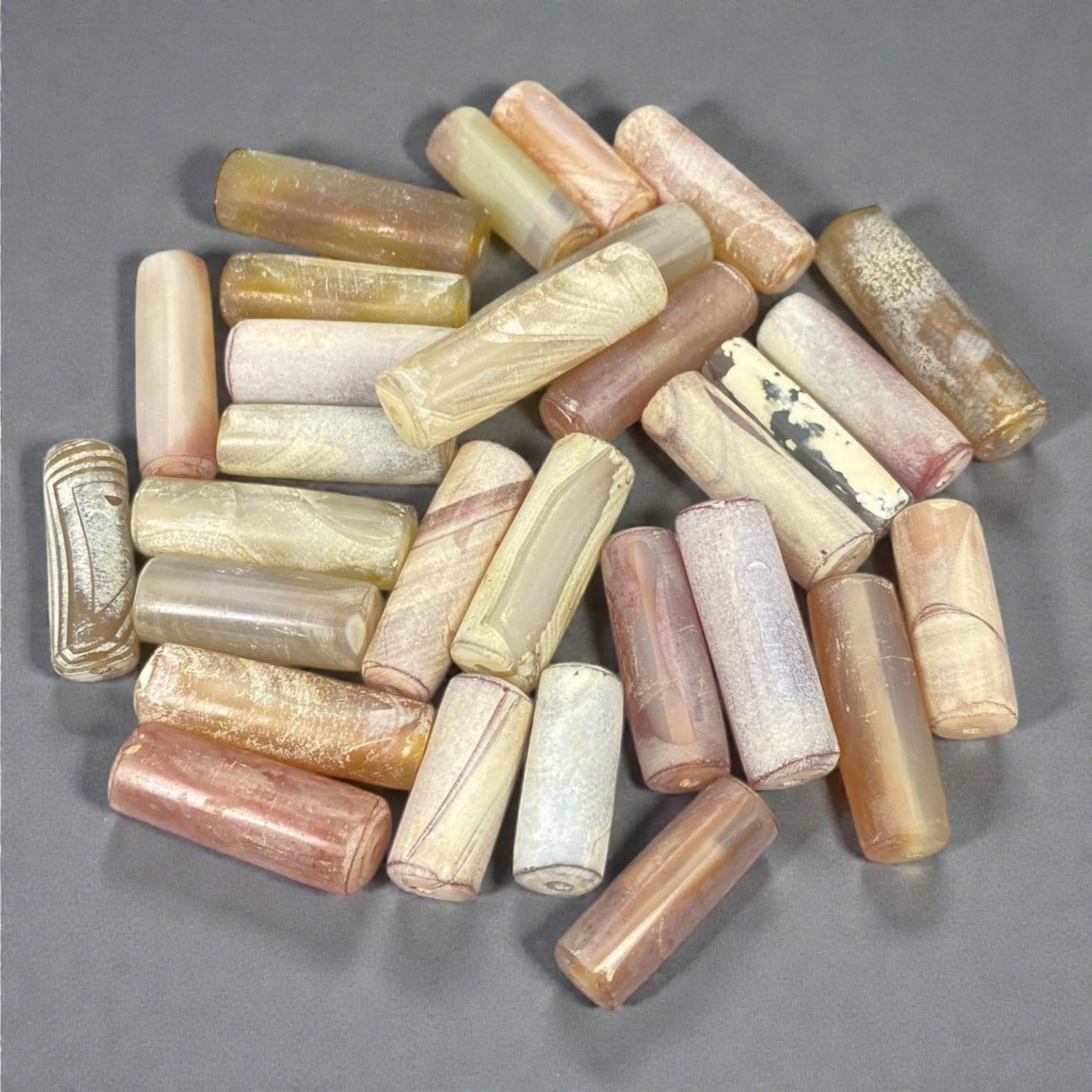 A Group of Ancient Agate Beads, 1st Millennium BCE-1st Millennium CE, 10W: The group comprises twenty-nine agate beads of predominantly cylindrical and short barrel form, carved from translucent to semi-opaque chalcedony in tones of cream, pale pink, beige, honey, and light