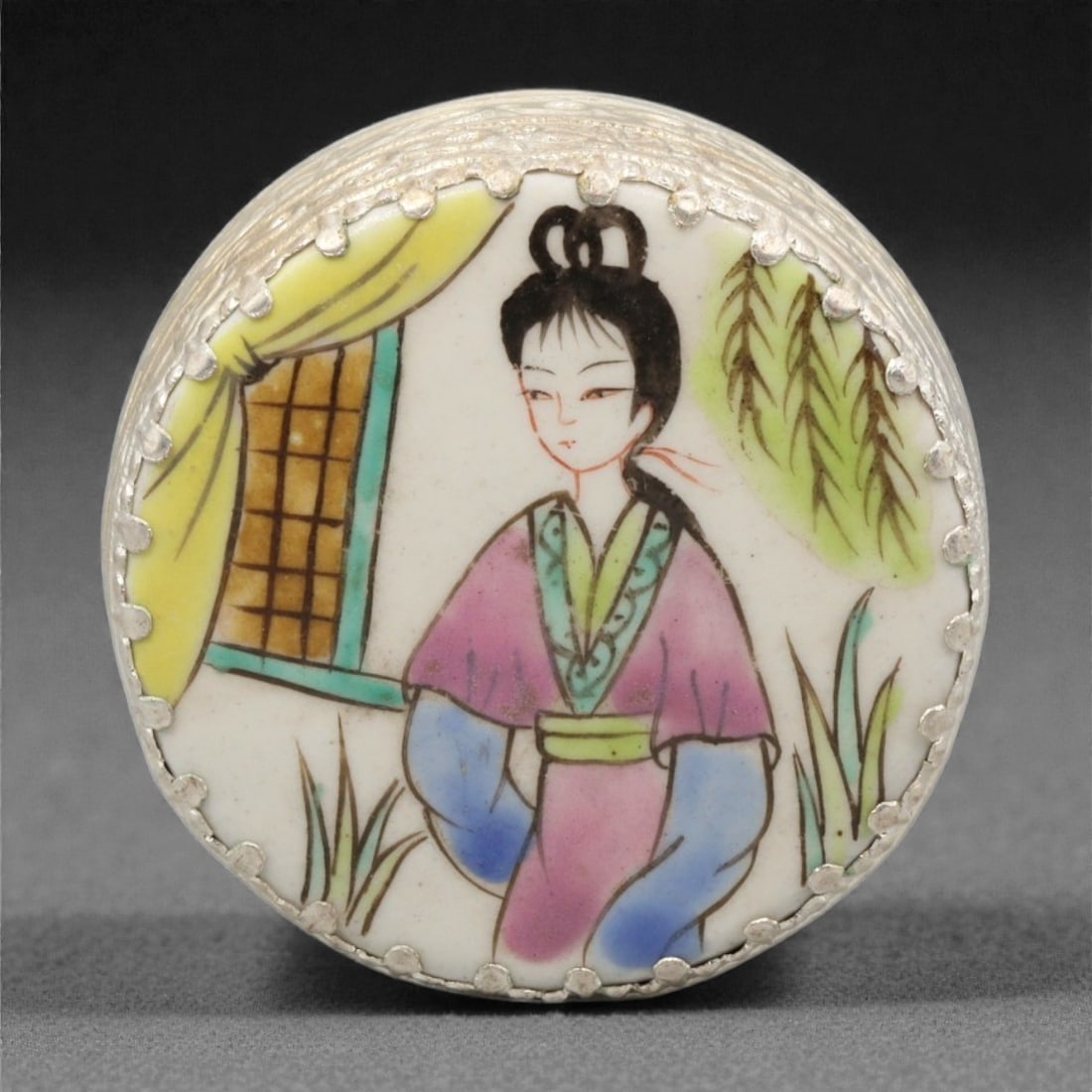 A Chinese Porcelain and Silvered Metal Trinket Box, 20th Century, 78YC: The box is formed of porcelain with a circular profile and shallow domed lid, encased within a silvered metal mount with a scalloped rim. The porcelain surface is painted in polychrome enamels with a