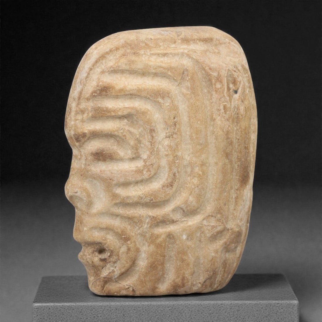 A Pre-Columbian Stone Head, 10th-15th Century, 24FM: Carved from light brown stone with natural patination and visible fissures, the object is shaped as a human head in profile, with stylized facial features including a prominent nose, full lips, and a