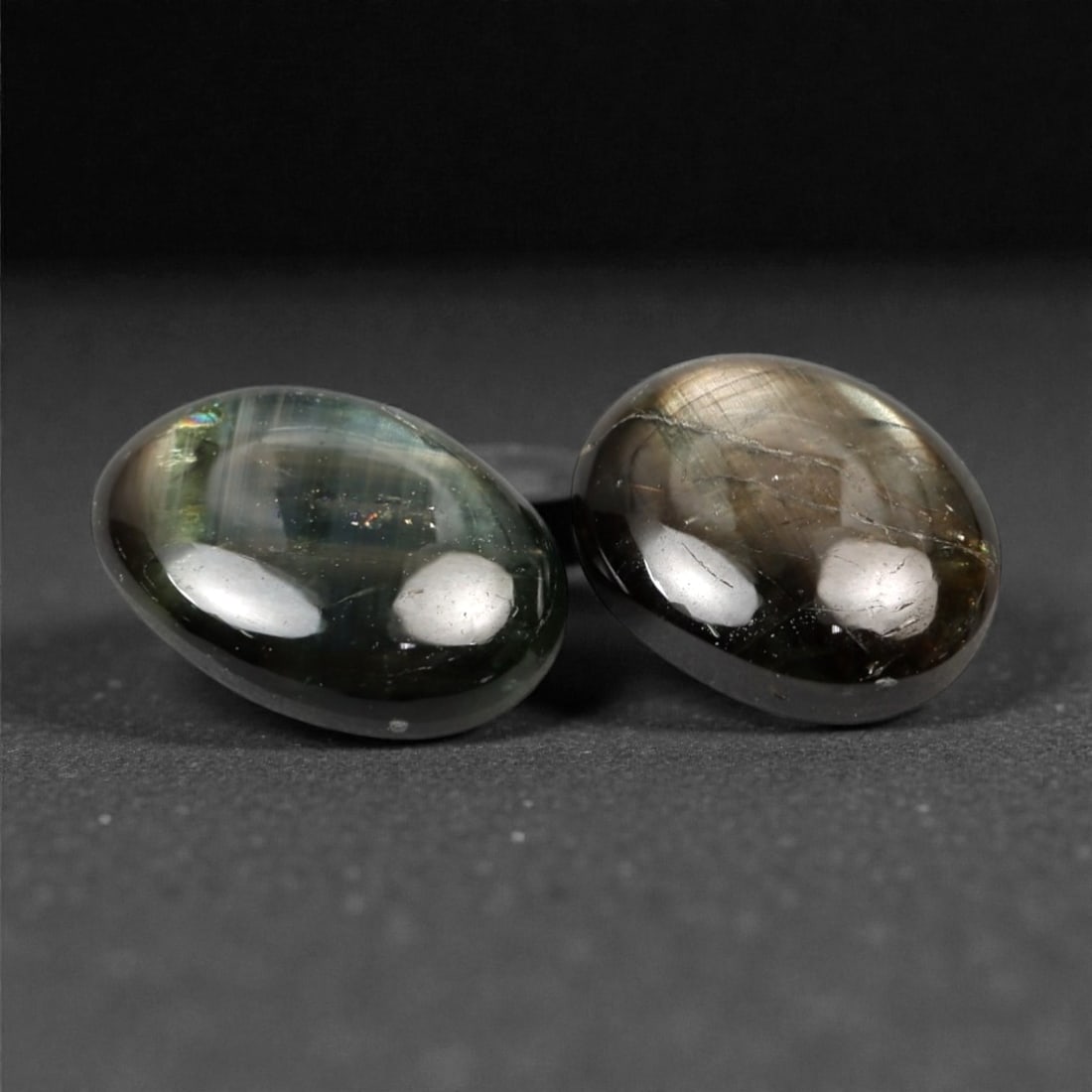 4.92 Carats Dark Greenish Grey Star Sapphire Parcel - Natural Sri Lankan Stones, 340A: This exceptional parcel of two loose star sapphires captivates with their deep, earthy greenish-grey hues and the subtle, luminous asterism that emerges under direct light. The smooth, cabochon-cut su