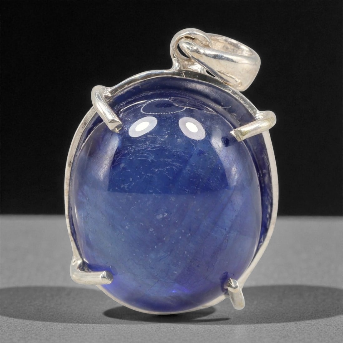 14.86 Carats Deep Blue Sapphire Cabochon Pendant - Sterling Silver Setting, 157A: This striking pendant features a substantial deep blue sapphire cabochon, set in a polished sterling silver frame stamped 925. The cabochon's smooth, domed surface radiates with a rich, velvety blue h
