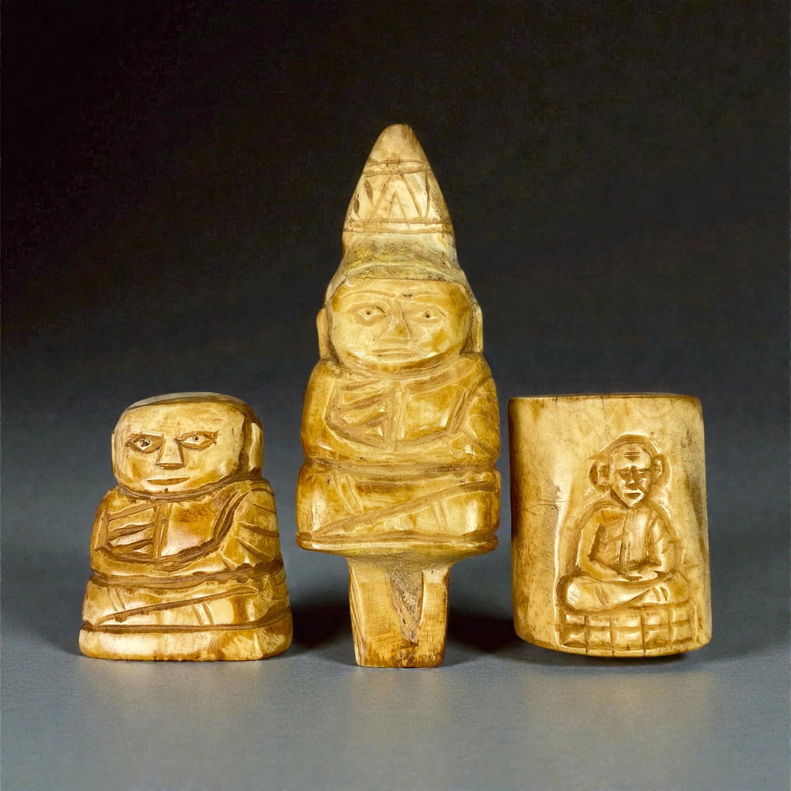 A Group of Three Thai Bone Carvings, 20th Century, 4W: Comprising three carved bone objects of varying scale, the group includes two figural carvings and one cylindrical vessel decorated in low relief. Executed in pale honey to light brown bone with visib