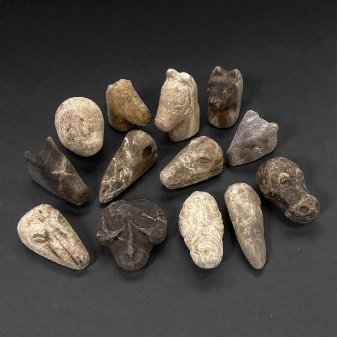 A Group of Near Eastern Stone Zoomorphic Figurines, 81Z: This group of thirteen small Near Eastern stone zoomorphic figurines is carved from dense, naturally variegated stone ranging in color from pale beige and buff to deep brown and charcoal gray. The ass