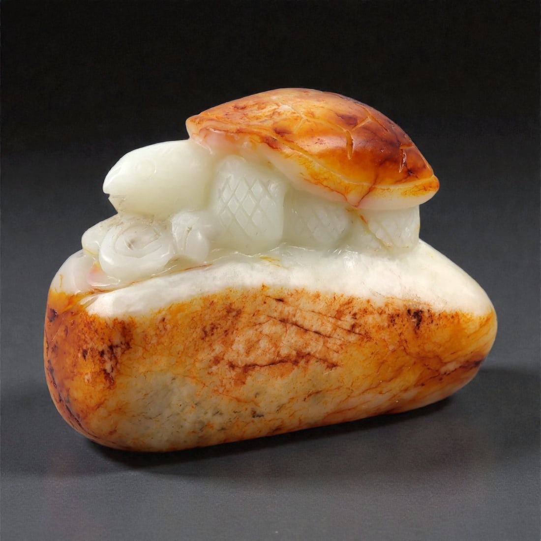 A Chinese Hetian Jade Tortoise Figure, 20th Century, 59FB: Carved from a single piece of bi-colored Hetian jade, the figure utilizes the natural creamy white body of the stone contrasted with a warm russet-brown skin. The composition depicts a recumbent torto