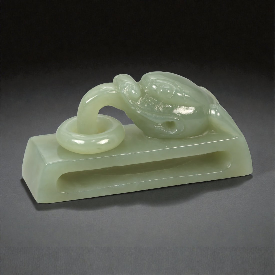 A Chinese Nephrite Jade Beast-Head Belt Hook, 20th Century, 1YA: Carved from pale celadon nephrite jade with soft translucency and subtle tonal variation, the object is formed as a belt hook with a sculpted beast head terminal. The beast head is rendered with round