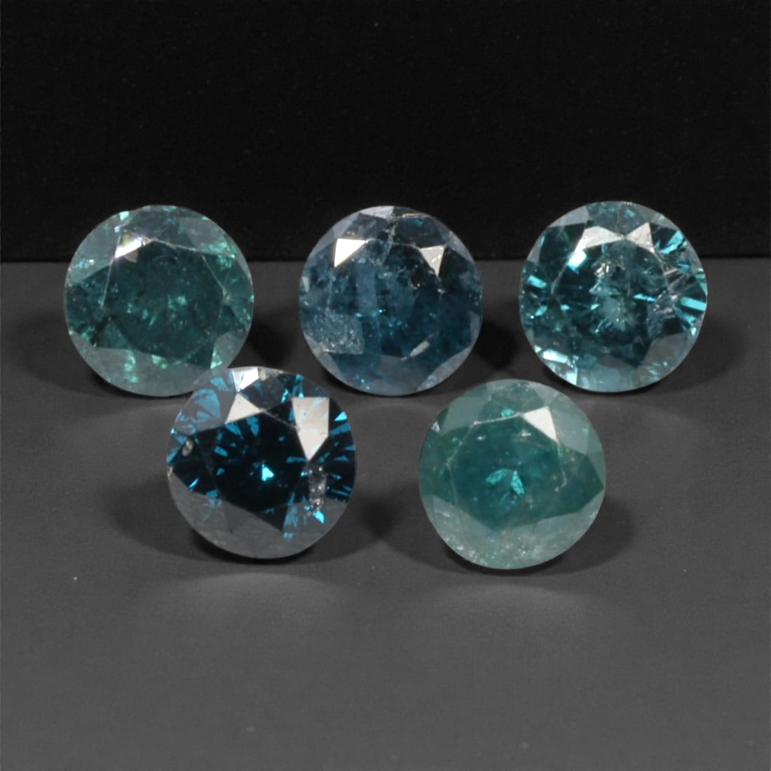 5 Pieces Irradiated Blue Diamond Parcel - Round Brilliant Cut, 2.4mm, 255A: This striking parcel of five loose irradiated blue diamond gems captivates with a vivid, cool blue hue that evokes the intensity of a deep ocean and the clarity of a winter sky. Each stone is cut in a