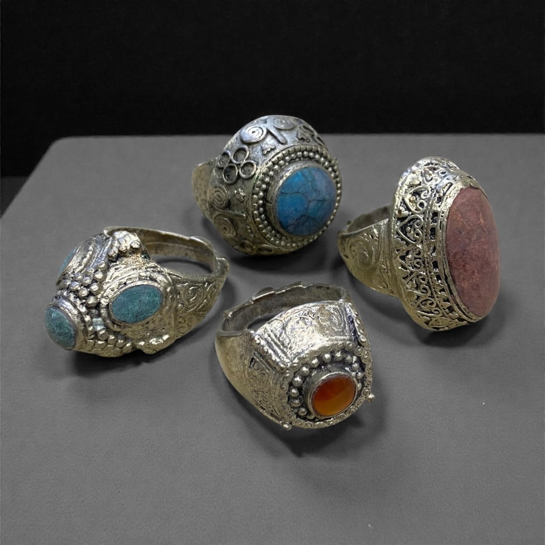 A Group of Four Antique Silvered Bronze Rings, 19th Century, Size 8-8.5US, 58g, 59AA: Each ring is crafted from silvered bronze, featuring ornate metalwork including filigree, repousse, and granulation details. The bezels are set with composite stones, the surfaces exhibit minor patina