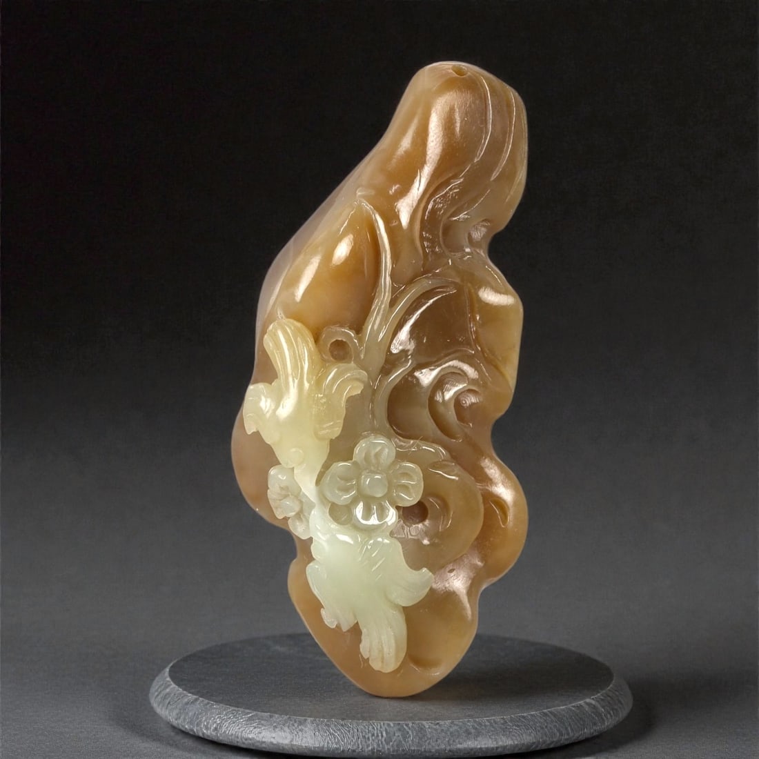 A Chinese Nephrite Jade Pendant with Bird and Floral Motifs, 20th Century, 41FA: Carved from two-toned nephrite jade displaying warm brown and pale celadon hues with natural translucency, the pendant is worked in relief to depict a bird perched among flowering branches and scrolli