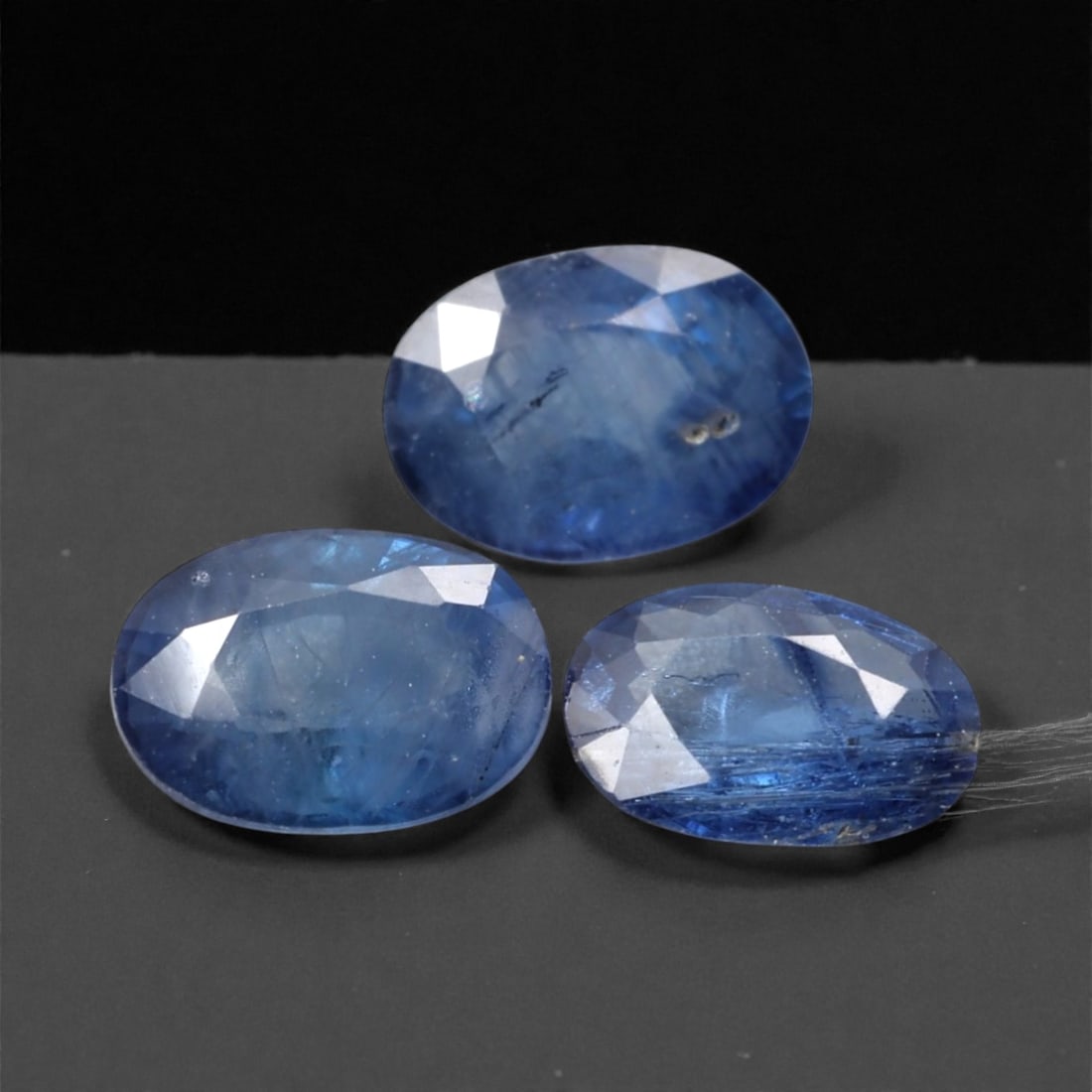 3.11 Carats Medium Blue Sapphire Selection - Natural Madagascan Stones, 312A: This curated selection of three oval-cut sapphires presents a serene, medium-blue hue reminiscent of twilight skies over tropical waters. Each stone is faceted to maximize light reflection, with a sof