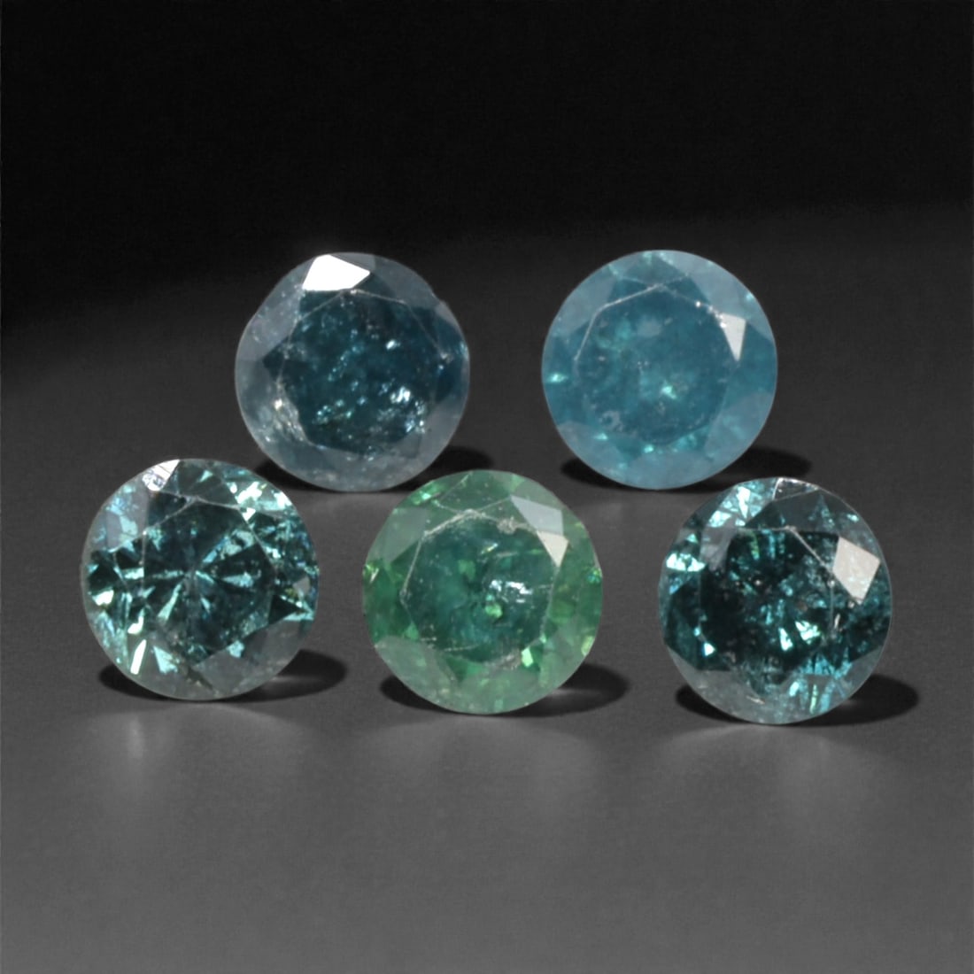 5 Pieces Irradiated Blue Diamond Parcel - Round Brilliant Cut, 2.4mm, 253A: This striking parcel of five loose irradiated blue diamond gems captivates with a vivid, cool blue hue that evokes the intensity of a deep ocean and the clarity of a winter sky. Each stone is cut in a