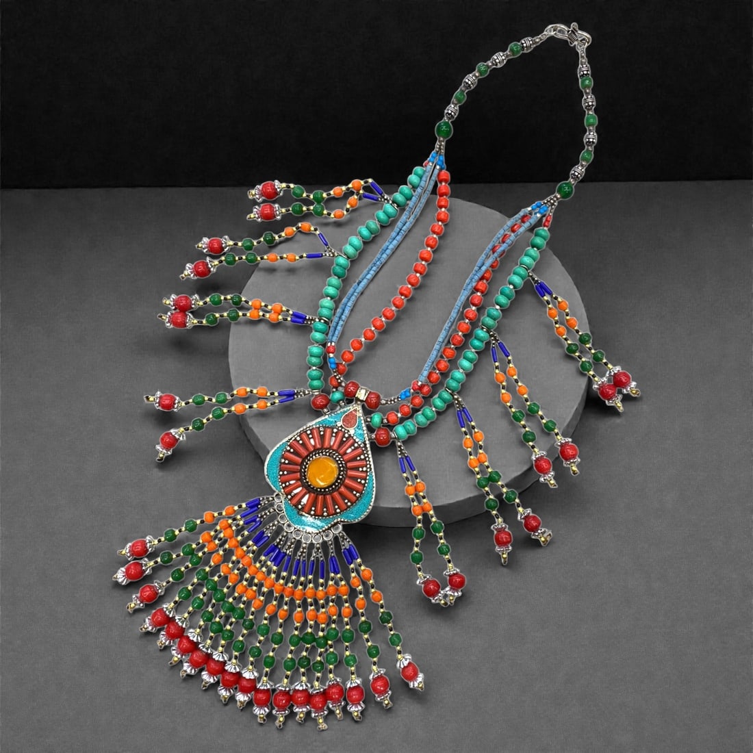 A Vintage Tibetan Composite Bead and Metal Necklace, 20th Century, 232g, 58AA: The necklace features a silver-toned metal base, with a central pendant inlaid with simulated coral, turquoise, and an amber-colored resin cabochon, surrounded by enameled detailing. Multiple strands