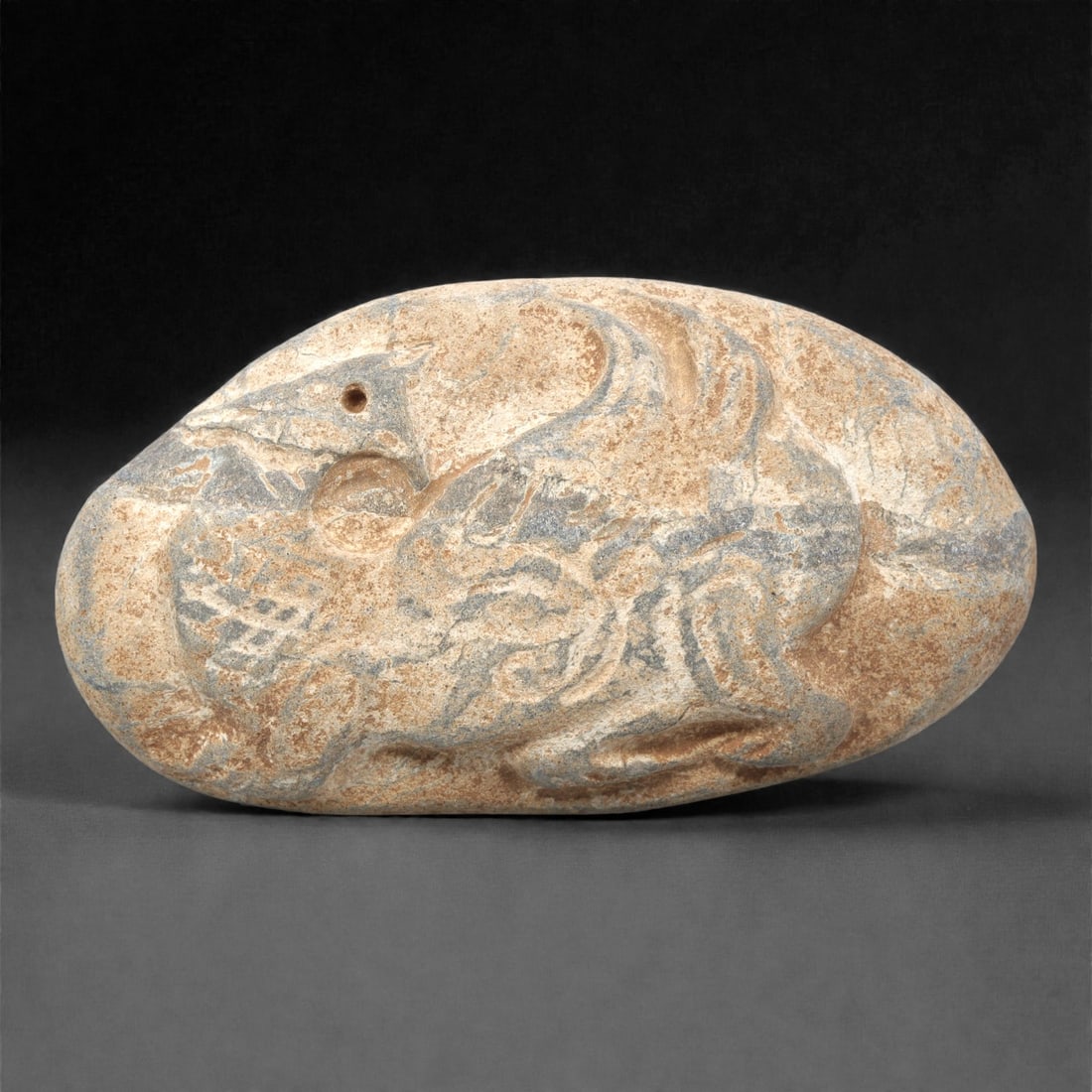 A Byzantine Stone Zoomorphic Relief, 7th-9th Century, 20ZH: Carved from a light beige stone with natural grey and brown patination, the relief is formed as an oval plaque. The surface depicts a composite zoomorphic creature in low relief, with a bird-like head