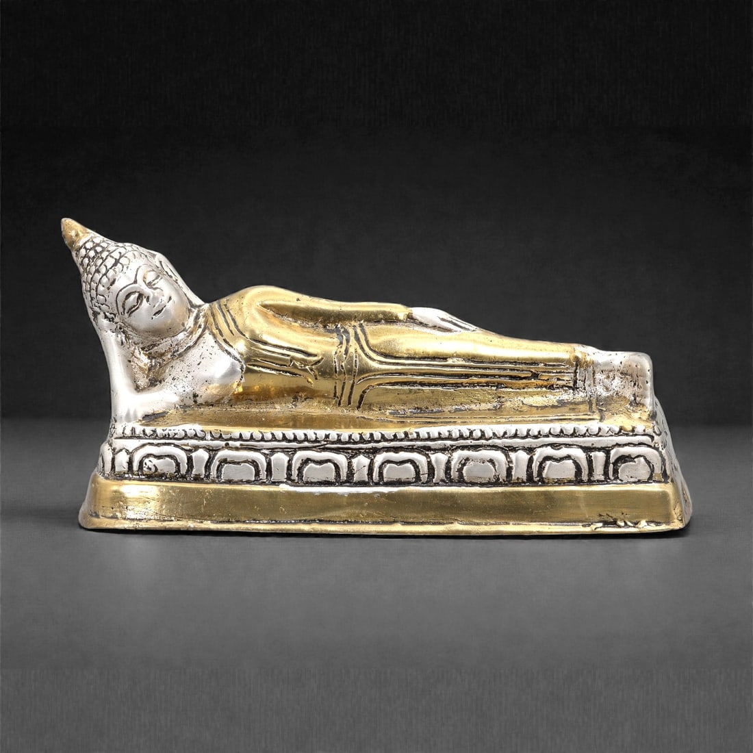 A Gilt and Silvered Bronze Reclining Buddha Figure, 20th Century, 17FJ: The figure is cast in bronze and finished with gilt and silvered surfaces. It depicts the Buddha reclining on his right side, with the head supported by the right hand and the body extended in a relax