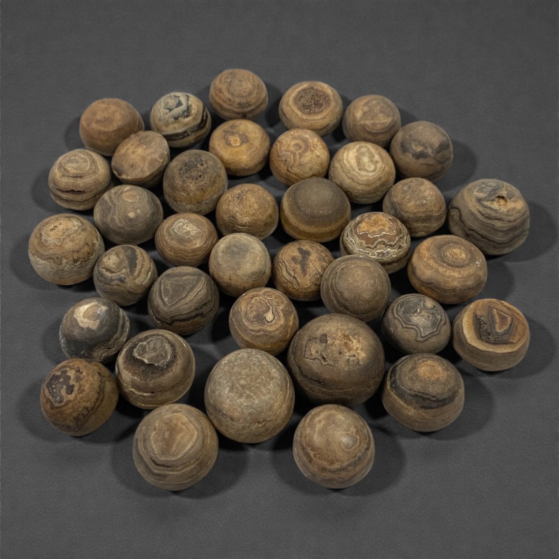 A Group of Tibetan Luk Mik ("Goat's Eye") Agate Beads, 19th-20th Century, 50V: Comprising thirty-seven spherical and near-spherical beads carved from agate, the group is distinguished by pronounced concentric banding and circular "eye" formations characteristic of Luk Mik ("goat