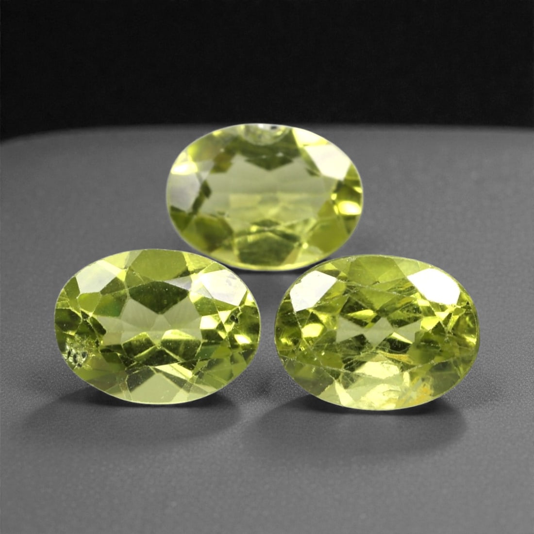 4.10 Carats Bright Green Peridot Selection - Natural Pakistani Stones, 301A: This curated selection of three oval-cut peridot gems radiates with a vibrant, lime-green hue, evoking the lush vibrancy of sunlit tropical foliage. Each stone is precision-faceted to maximize light d