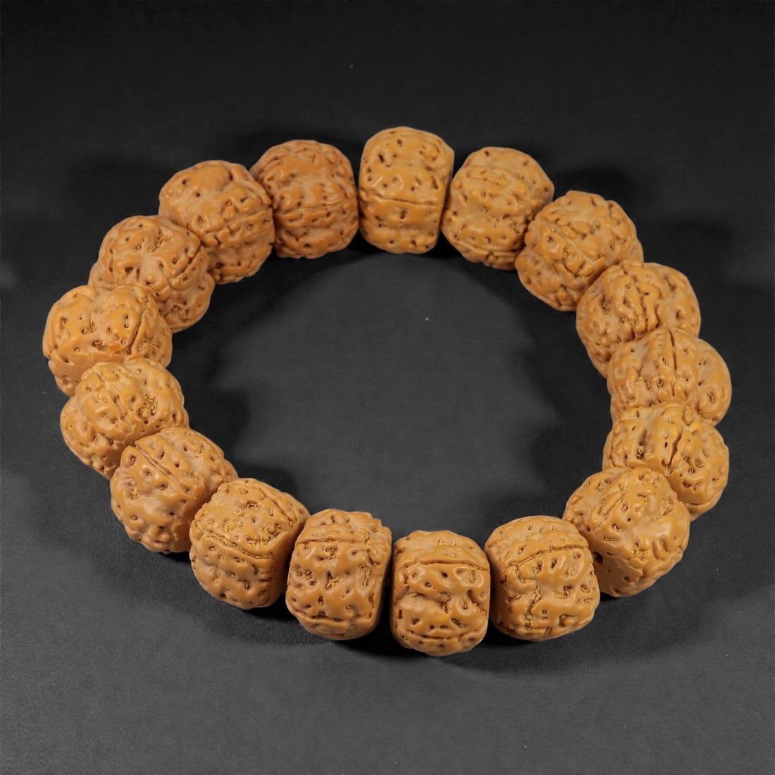 A Seed Bead Bracelet, 20th-21st Century, 75YB: Composed of a continuous strand of carved natural seeds, drilled and strung to form a circular bracelet. Each bead is of rounded, slightly faceted form, with a dense surface of natural pits, fissures,