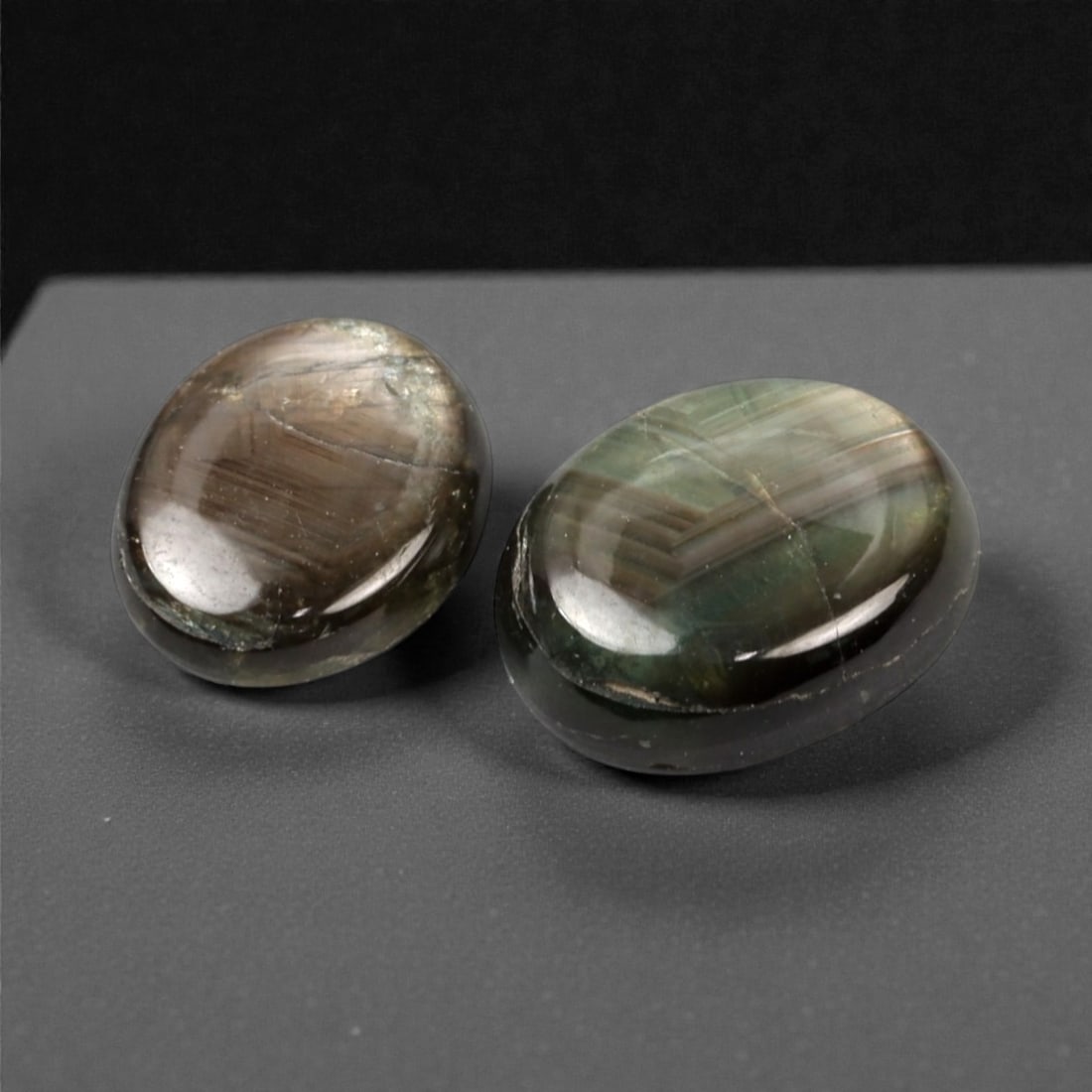 5.62 Carats Star Sapphire Selection - Natural Ceylon Origin, 320A: This curated selection of two star sapphires showcases the ethereal, natural beauty of these gemstones, with a muted, earthy palette of deep brown and rich greenish tones. Each cabochon-cut stone exhi