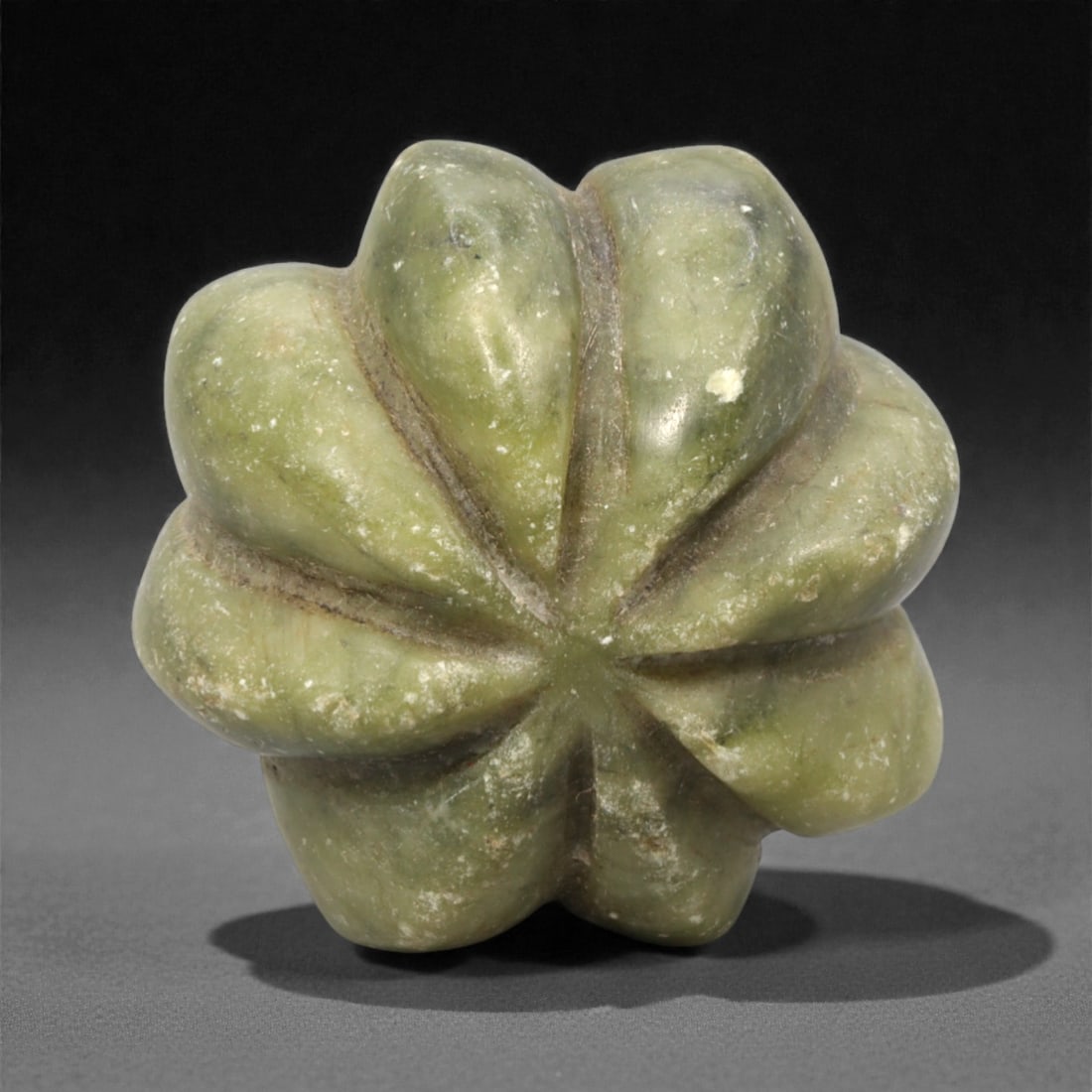 A Chinese Hetian Jade Melon-Shaped Bead, 20th Century, 91FH: Carved from greenish Hetian jade with lighter and darker tonal variations and scattered natural inclusions, the object is modeled in the form of a melon with a rounded, lobed body. The surface is arti