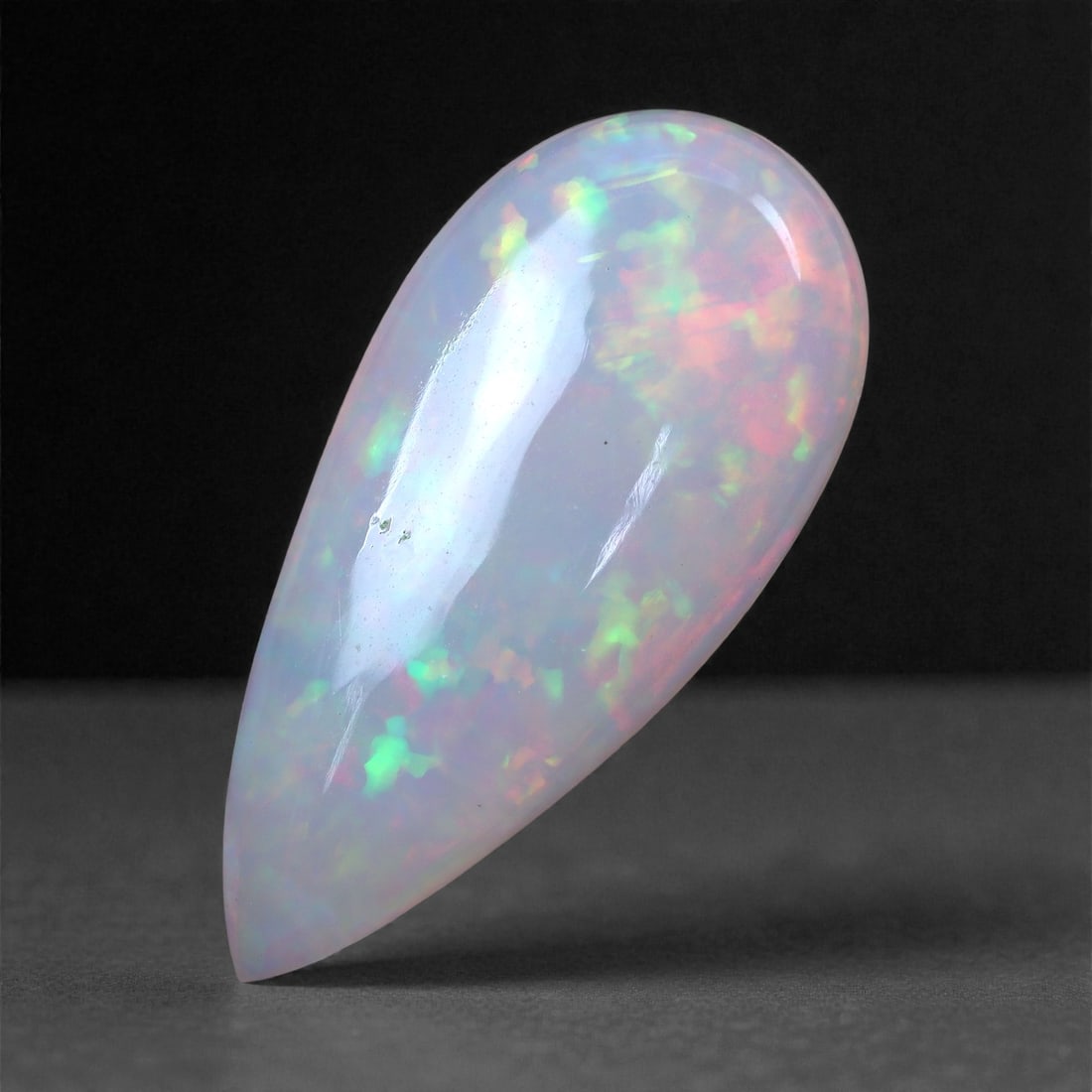 4.21 Carats Long Pear-Shaped Welo Opal - Natural Ethiopian Gems 21.3 x 10.2 x 4.3 mm, 3XH: This 4.21 carat Ethiopian Welo opal captivates with its elongated pear silhouette and an impressive display of broadflash play-of-color. Its pastel palette is peppered with vivid bursts of neon green,
