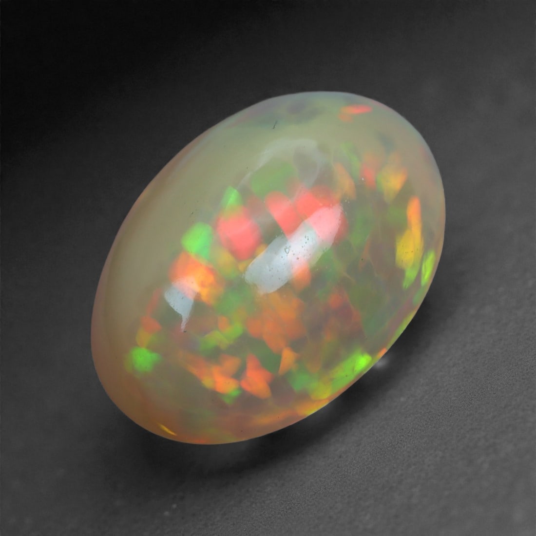 3.11 Carats Play-of-Color Welo Opal - Natural Ethiopian Gem 13x9mm, 42XA: This captivating Welo opal gleams with a luminous cascade of multi neon color that ripple across the stone's surface with every movement. The play-of-color is vivid and well-distributed, presenting a