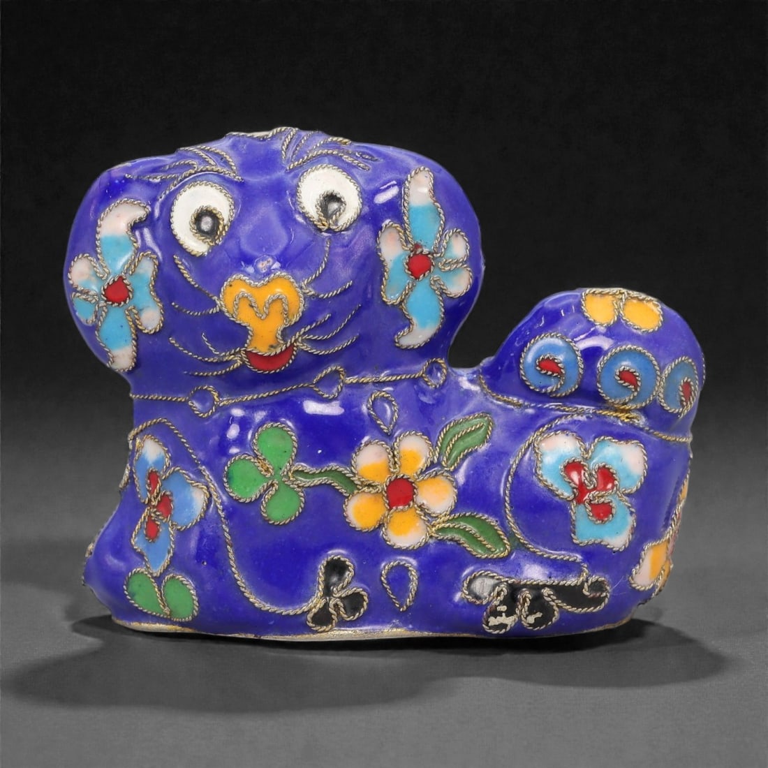 A Chinese Cloisonne Enamel Pekingese Dog Effigy, 20th Century, 9FH: Constructed from a copper alloy body and decorated with cloisonne enamel, the object is formed as a recumbent Pekingese dog with the head raised and the body compactly modeled. Fine metal wire cloison