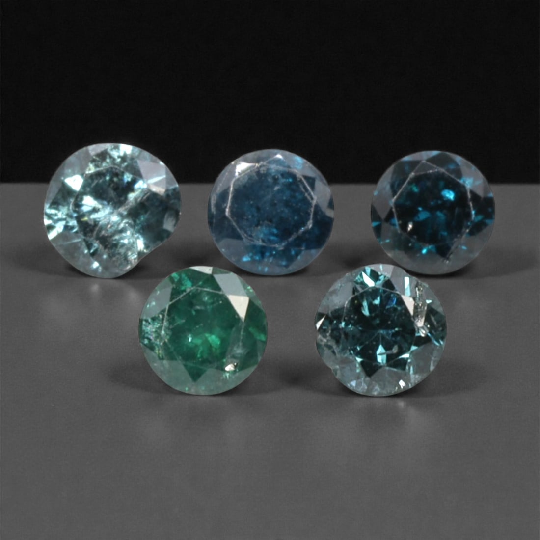 5 Pieces Irradiated Blue Diamond Parcel - Round Brilliant Cut, 2.4mm, 249A: This striking parcel of five loose irradiated blue diamond gems captivates with a vivid, cool blue hue that evokes the intensity of a deep ocean and the clarity of a winter sky. Each stone is cut in a