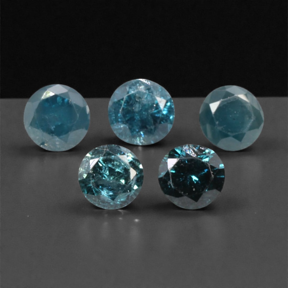 5 Pieces Irradiated Blue Diamond Parcel - Round Brilliant Cut, 2.4mm, 246A: This striking parcel of five loose irradiated blue diamond gems captivates with a vivid, cool blue hue that evokes the intensity of a deep ocean and the clarity of a winter sky. Each stone is cut in a