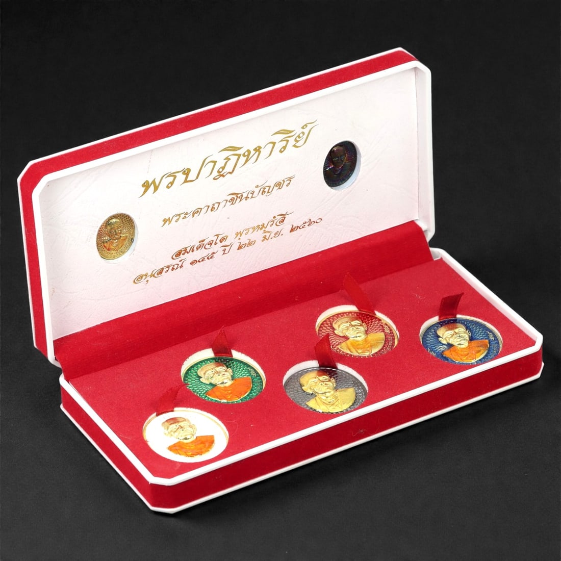 A Thai Bronze Monk Amulet Set, 20th-21st Century, 51FJ: Cast in bronze and finished with polychrome enamel, the set comprises six circular portrait amulets depicting a Buddhist monk in high relief, shown in bust-length format wearing monastic robes. The fa