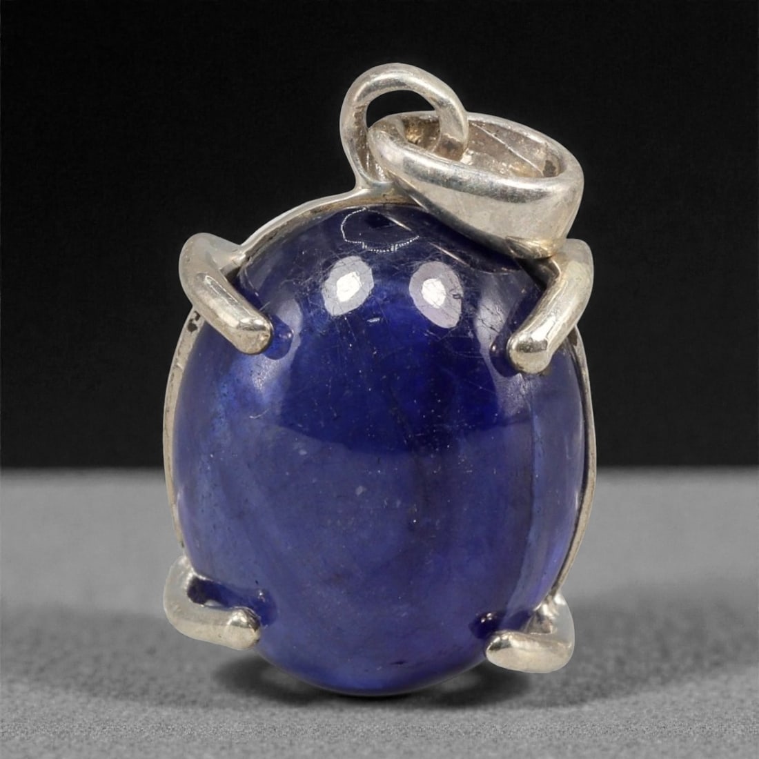 12.26 Carats Deep Blue Sapphire Cabochon Pendant - Sterling Silver Setting, 154A: This striking pendant features a substantial deep blue sapphire cabochon, set in a polished sterling silver frame stamped 925. The cabochon's smooth, domed surface radiates with a rich, velvety blue h