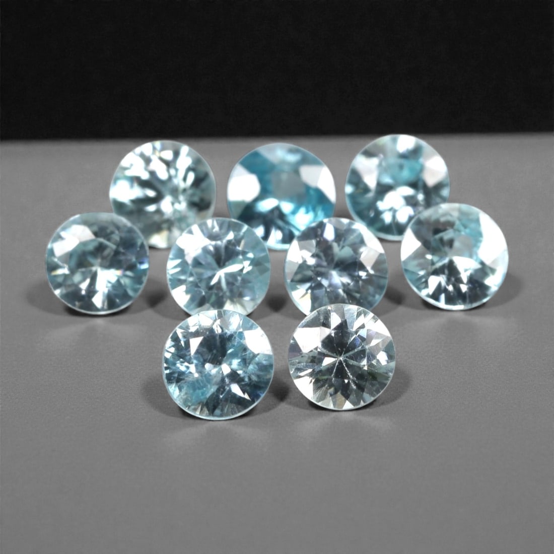 3.04 Carats Sky Blue Zircon Parcel - Natural Sri Lankan Stones, 339A: This luminous parcel of nine loose zircon gems dazzles with a soft, sky-blue hue that evokes the clarity of a bright, open sky. Each stone is cut in a well-proportioned round brilliant shape, with fac