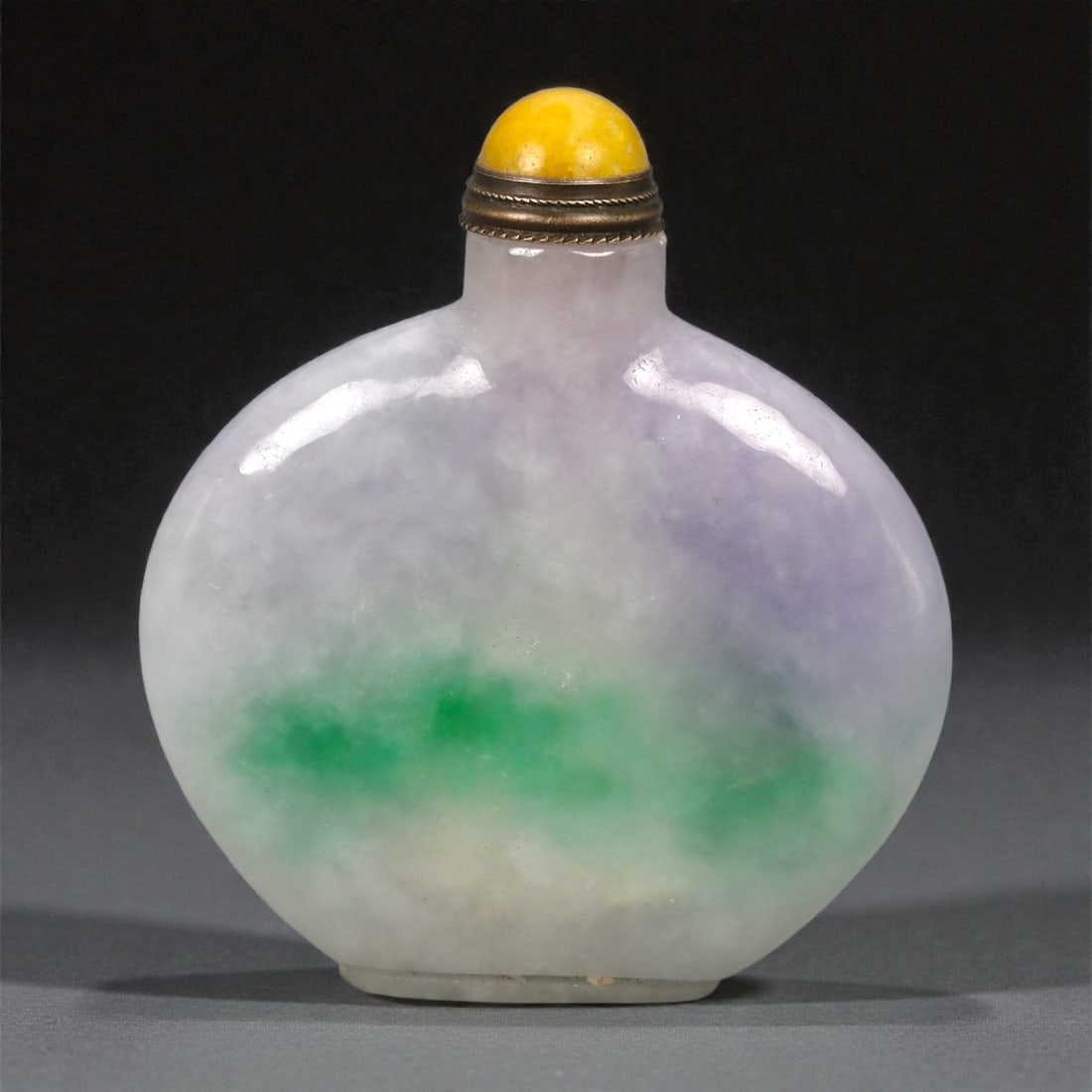 A Chinese Jadeite Snuff Bottle, Qing Dynasty, Late 19th-Early 20th Century, 14YB: Carved from translucent jadeite with mottled lavender and pale green inclusions, the bottle is worked in a flattened ovoid form with gently rounded shoulders rising to a short cylindrical neck. The ma