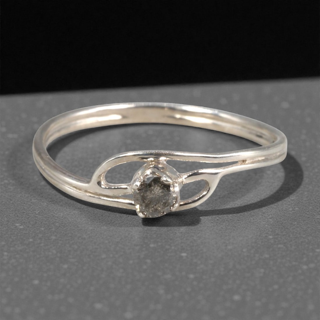 Sterling Silver (925) Ring with Salt-and-Pepper Diamond - Size 7 US, 127A: This modern ring is crafted from polished sterling silver, featuring a distinctive openwork split-shank design that frames the center stone. The centerpiece is a round-cut salt-and-pepper diamond, hel