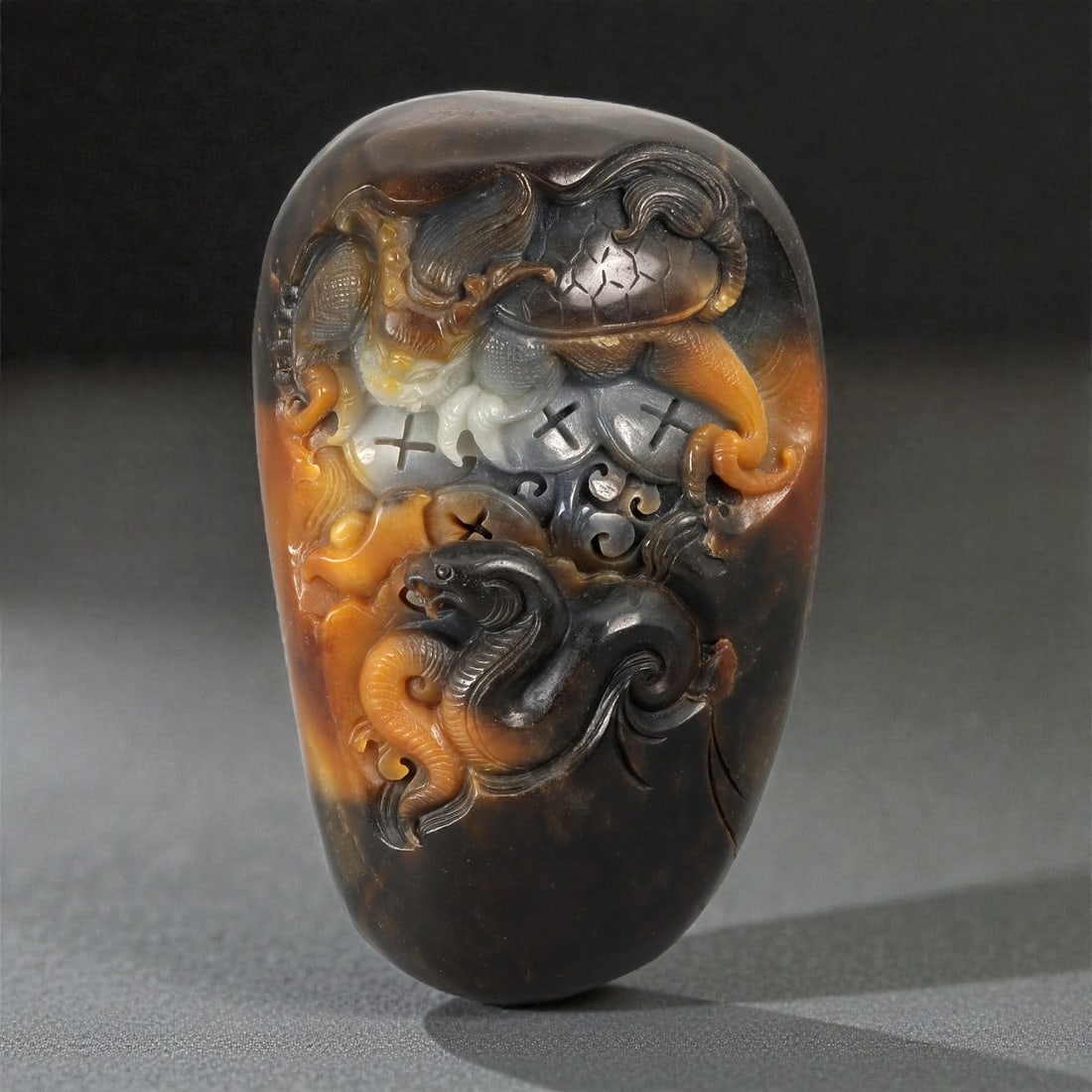 A Chinese Nephrite Jade Carving, 20th Century, 29FD: Carved from a single block of nephrite jade of Hetian type, the stone exhibits natural tonal variation ranging from dark grey to brown and amber hues, with areas of lighter translucency. The carving i