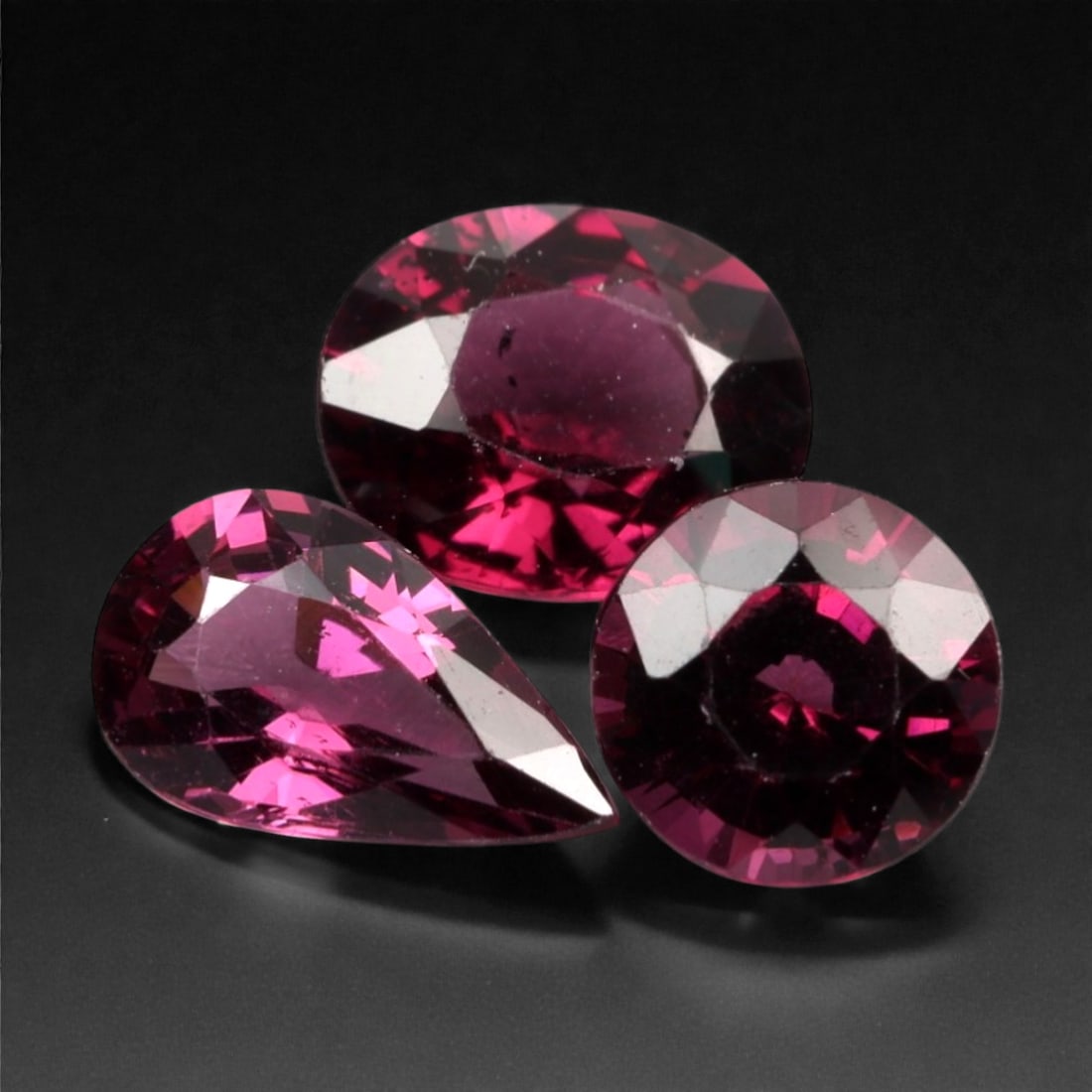 3.55 Carats Deep Pinkish Red Garnet Parcel - Natural Mahenge Stones, 321A: This striking parcel of three loose garnet gems captivates with a rich spectrum of deep pinkish-red hues, evoking the intensity of fine crimson and the warmth of glowing embers. Each stone is cut in a