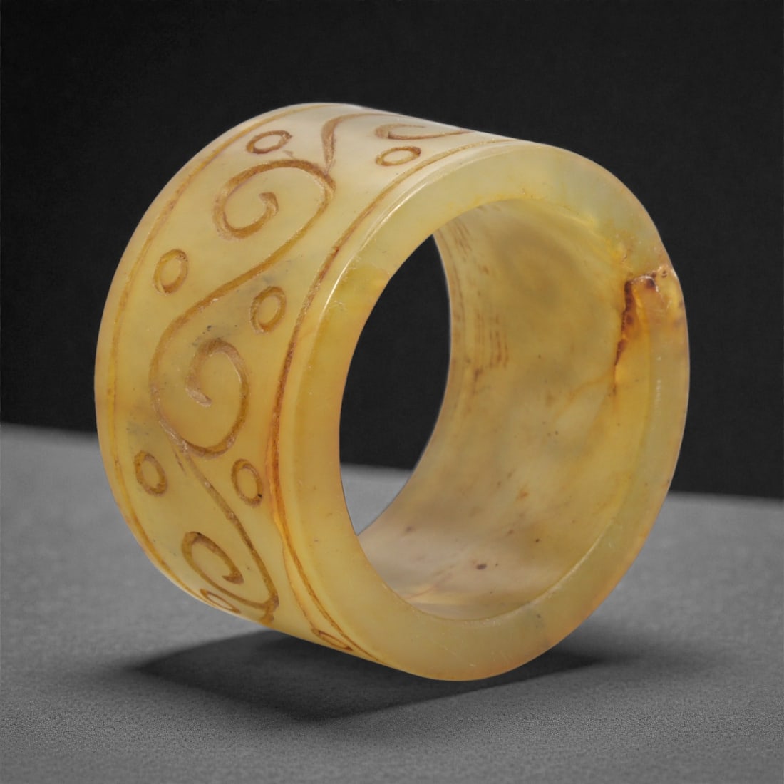 A Chinese Hetian Jade Cylindrical Ornament, 20th Century, 69FH: Carved from translucent yellow-toned Hetian jade with warm honey and amber hues, this object is formed as a thick-walled cylinder with a broad circular aperture and smoothly rounded rims. The exterior