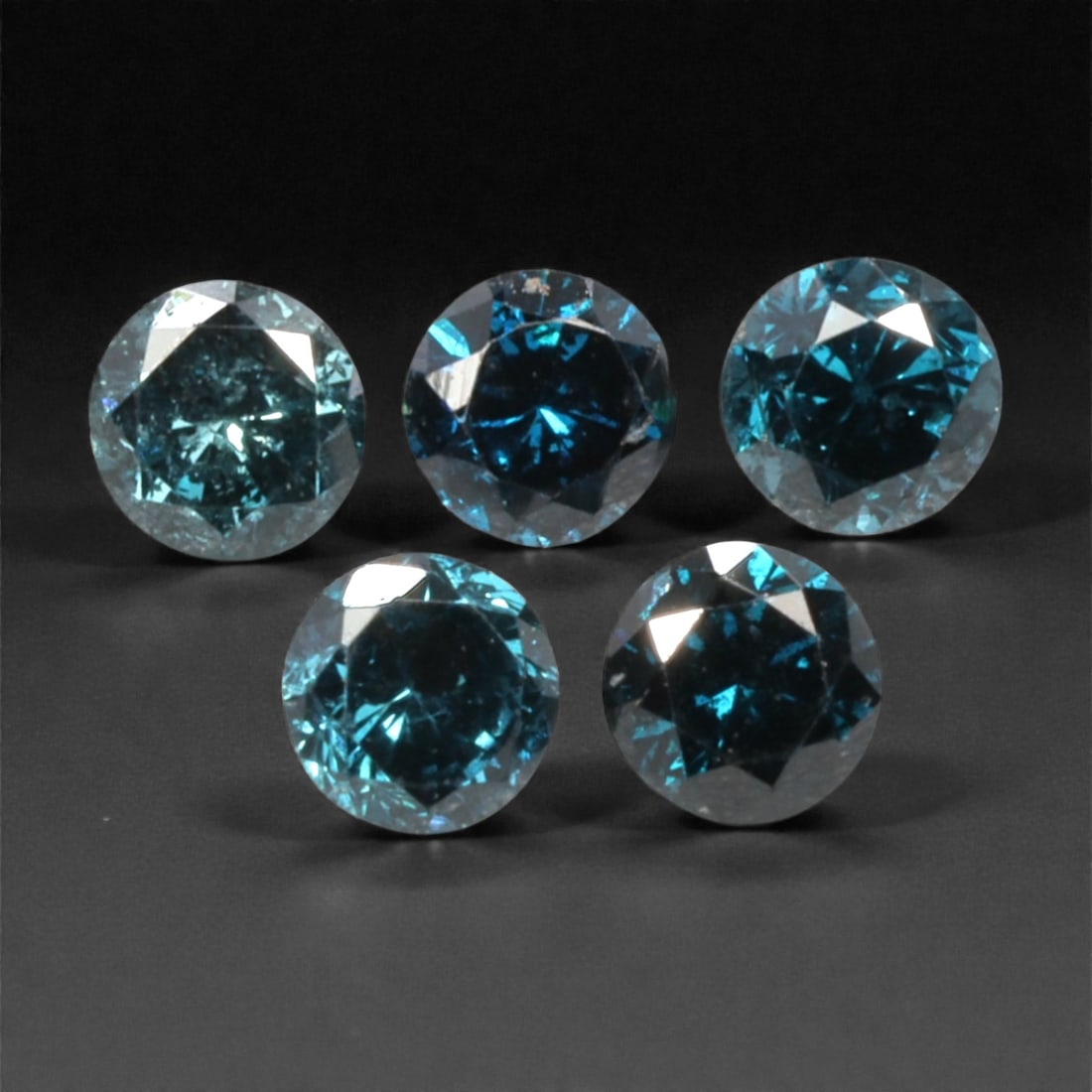 5 Pieces Irradiated Blue Diamond Parcel - Round Brilliant Cut, 2.4mm, 258A: This striking parcel of five loose irradiated blue diamond gems captivates with a vivid, cool blue hue that evokes the intensity of a deep ocean and the clarity of a winter sky. Each stone is cut in a