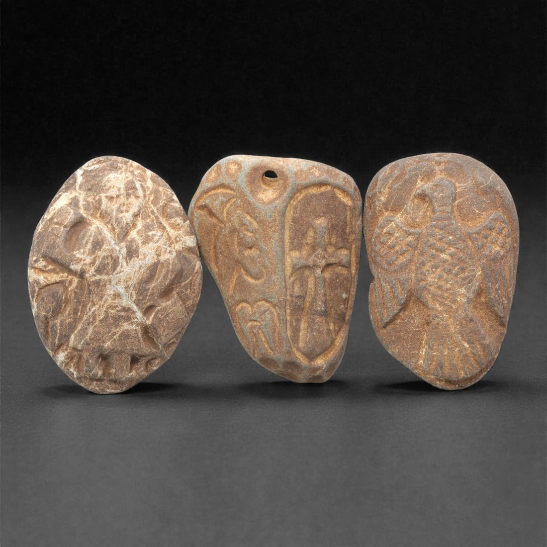 A Group of Three Christian Period Stone Carving Reliefs, 4th-7th Century CE, 4ZH: Comprising three distinct stone carving reliefs, each carved from brownish stone with natural color and texture variations. The first, of light brown stone with prominent white mineral inclusions and