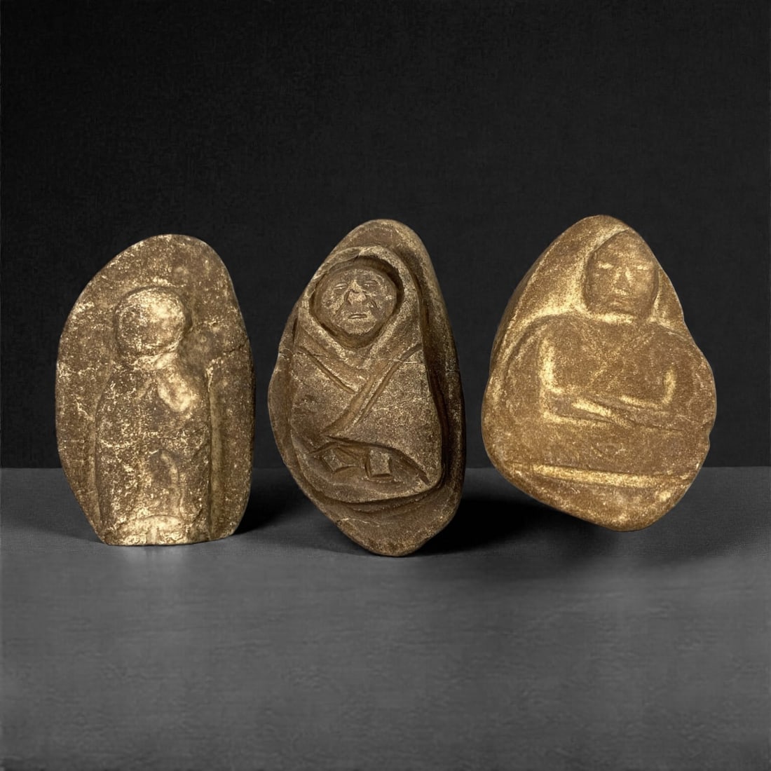 A Group of Three Edo Period Buddhist Stone Carvings, 17th-19th Century, 30FN: Carved from stone with natural tonal variation and surface wear, the three objects depict seated Buddhist figures in a meditative posture. The leftmost figure is set within an irregular, rounded stone