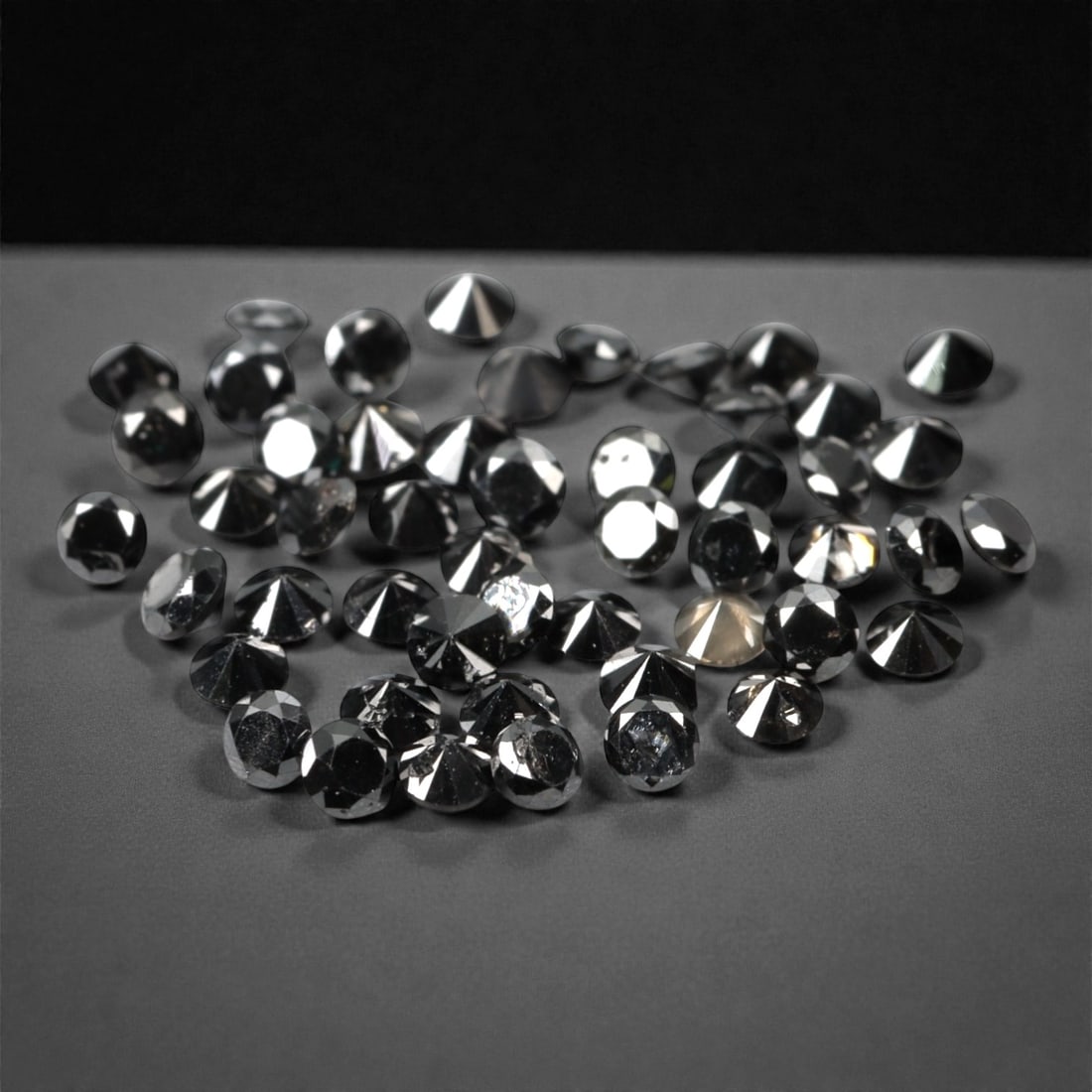 50 Pieces Black Diamond Parcel - Round Brilliant Cut, 1.7mm, 167A: This versatile parcel of 50 loose black diamond gems captivates with a deep, opaque black hue that evokes the intensity of polished obsidian and the mystery of a midnight sky. Each stone is cut in a w
