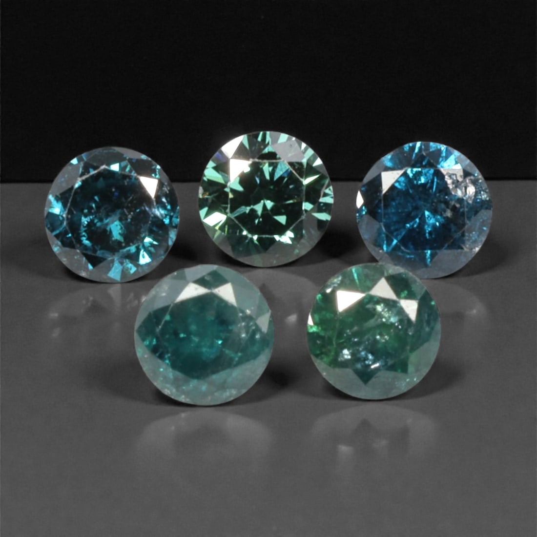 5 Pieces Irradiated Blue Diamond Parcel - Round Brilliant Cut, 2.4mm, 256A: This striking parcel of five loose irradiated blue diamond gems captivates with a vivid, cool blue hue that evokes the intensity of a deep ocean and the clarity of a winter sky. Each stone is cut in a