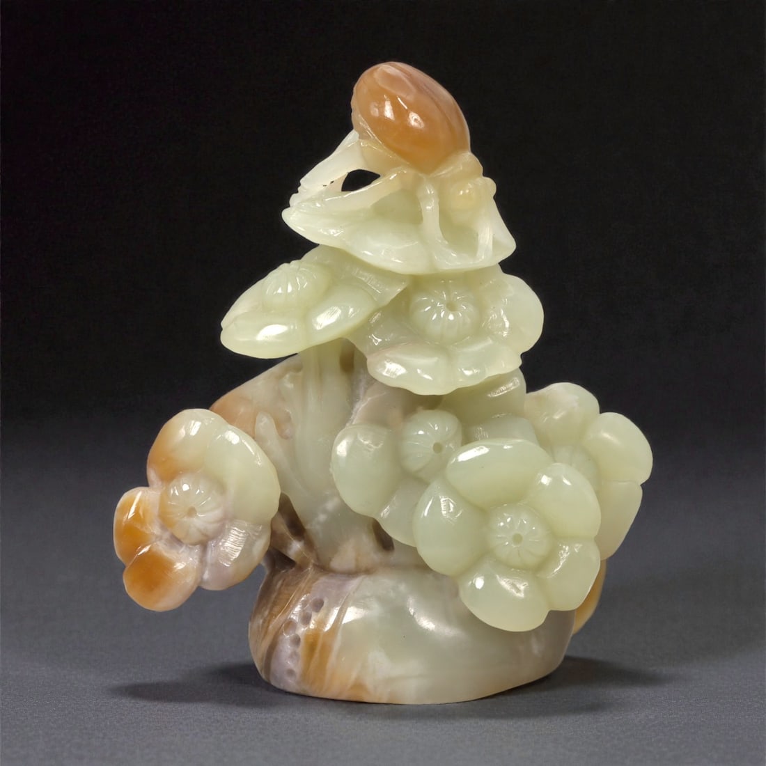 A Chinese Hetian Jade Carving of an Insect and Flowering Plant, 20th Century, 50FC: Carved from pale celadon Hetian jade with areas of warm russet and honey-brown skin, the sculpture represents a flowering plant surmounted by a small insect. The composition is worked fully in the rou